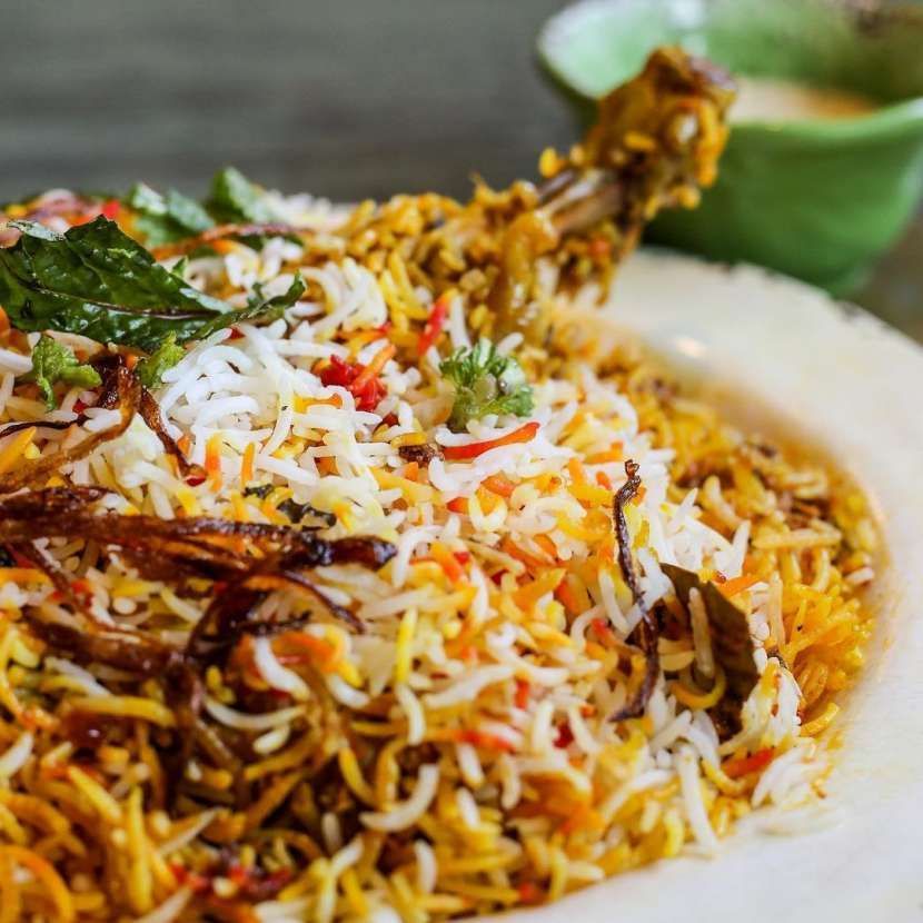 A close up of a plate of food with rice and vegetables on a table.
