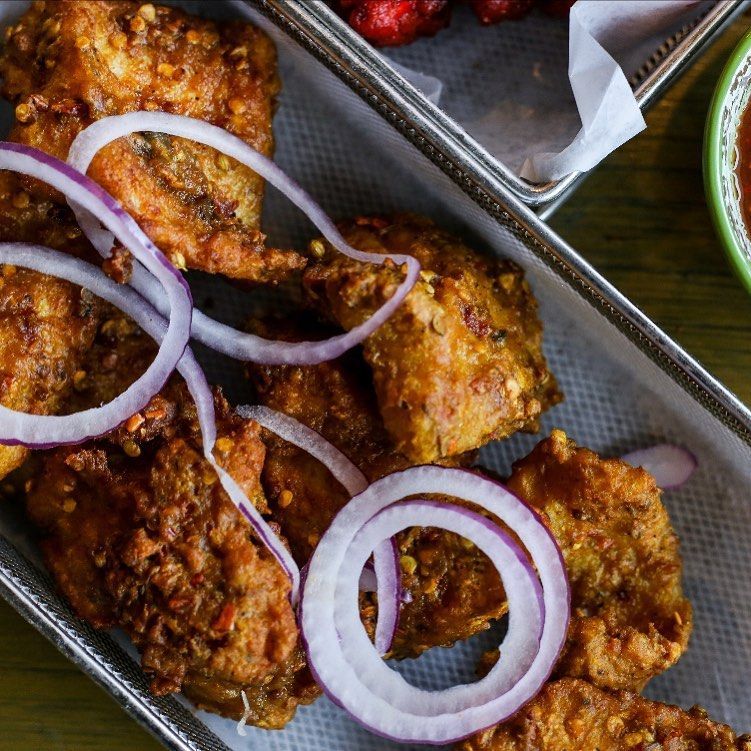 A tray of fried chicken with onions on a table