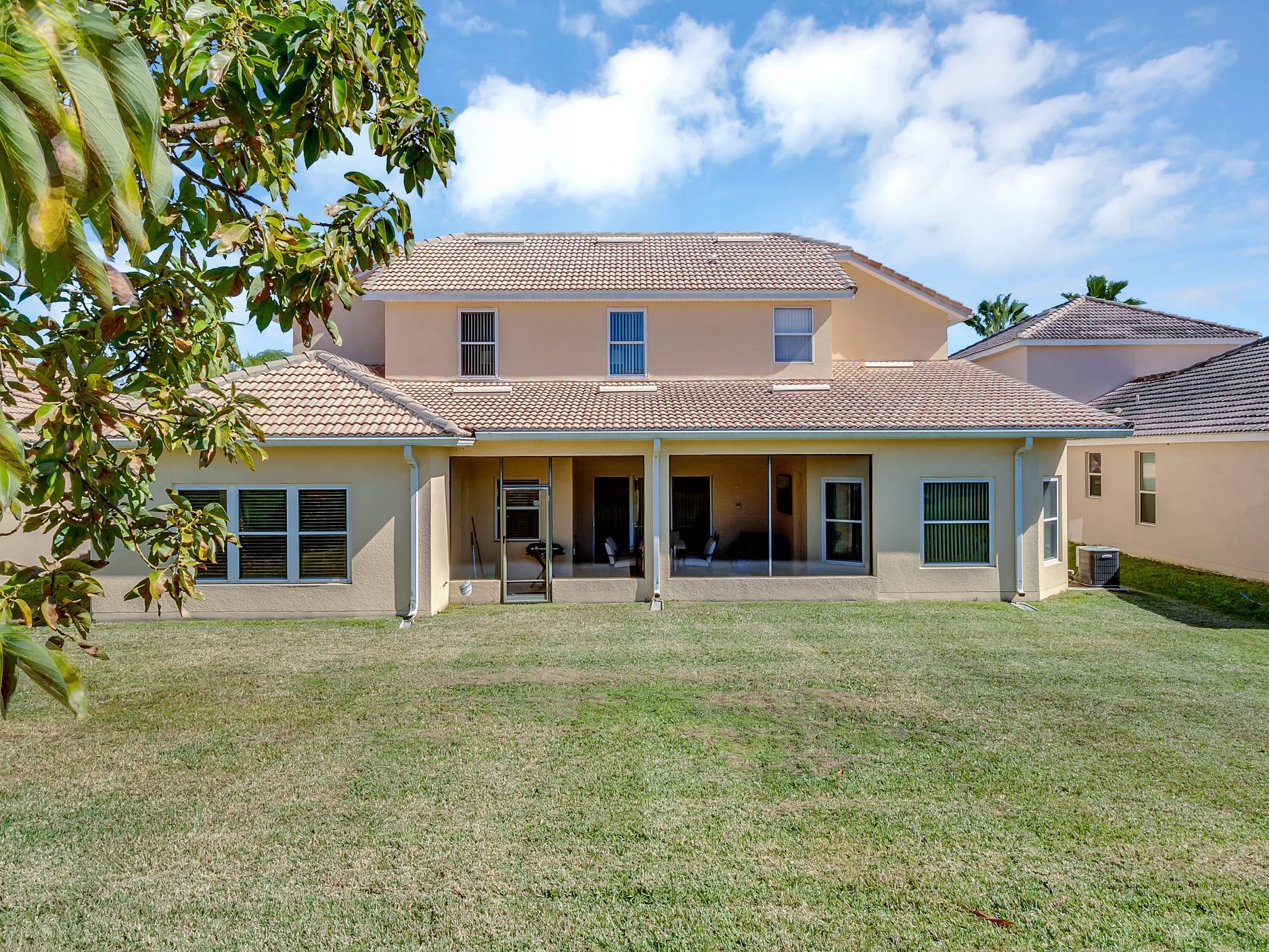 The back of a large house with a large lawn in front of it.