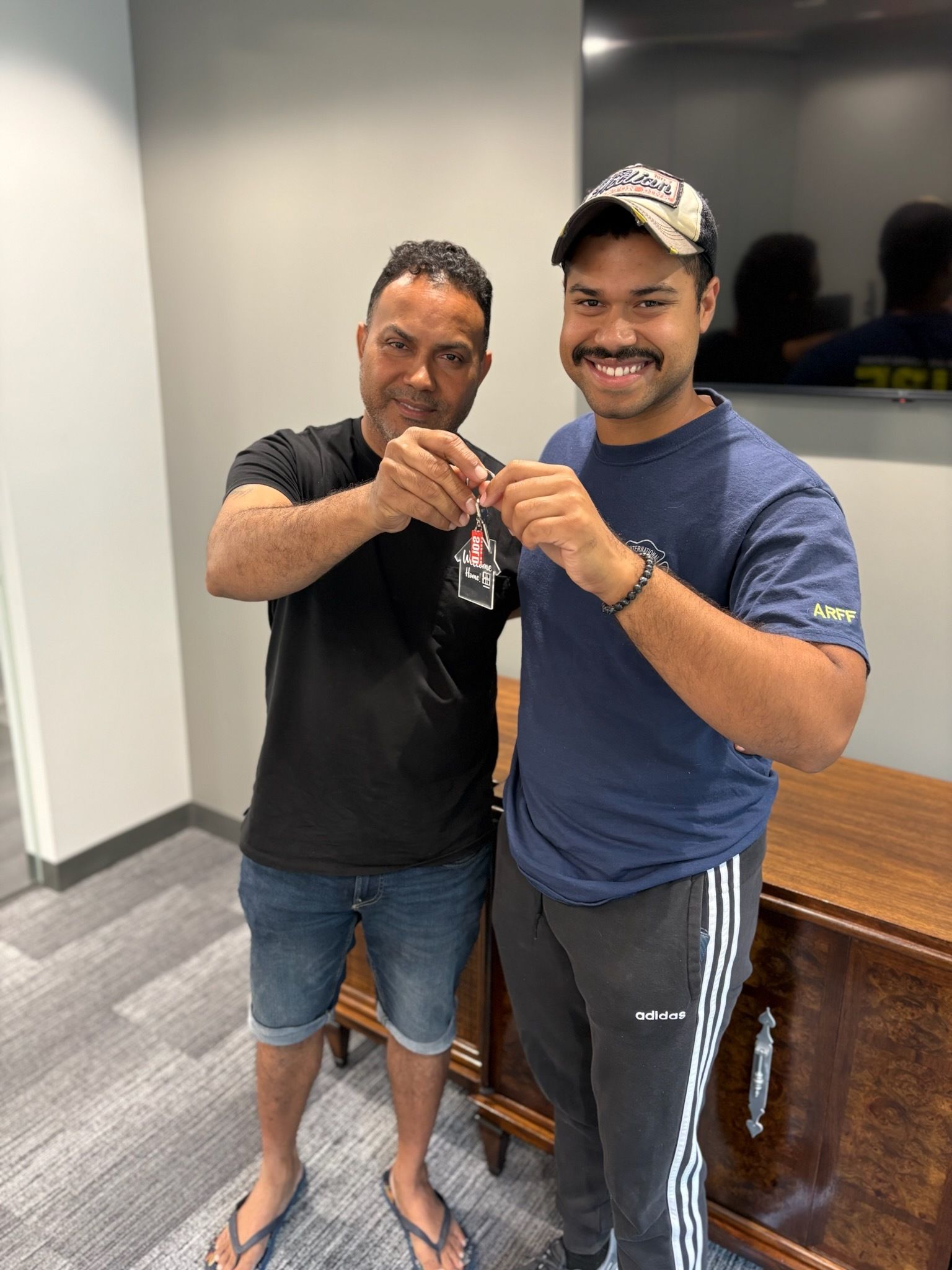Two men are standing next to each other in a room holding keys.