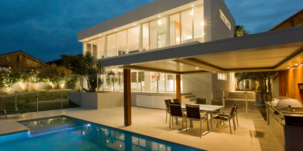 A large house  in Martin County, FL with a swimming pool and a table and chairs in front of it.
