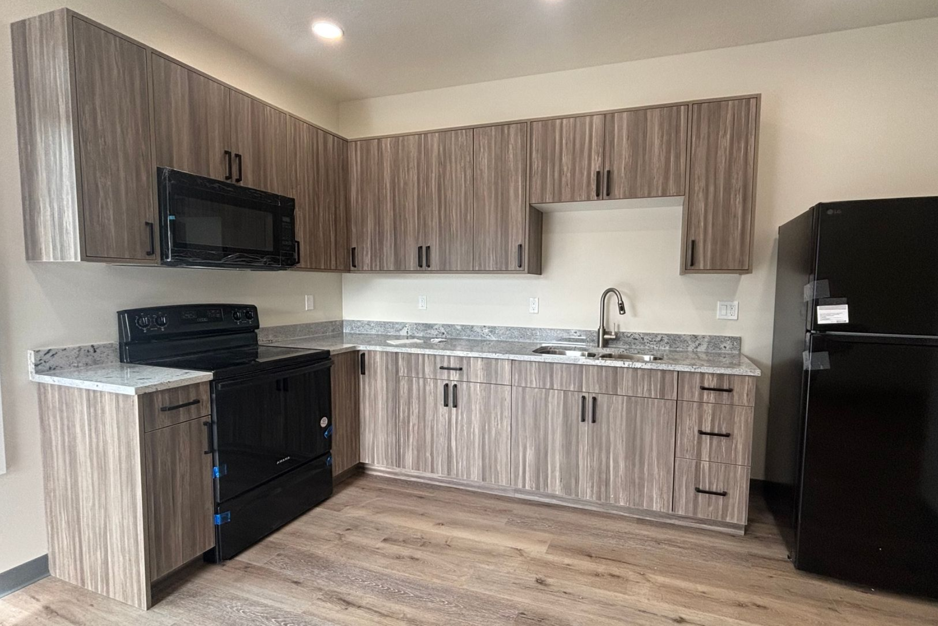 Small modern kitchen with wood cabinets, black appliances, and light countertops