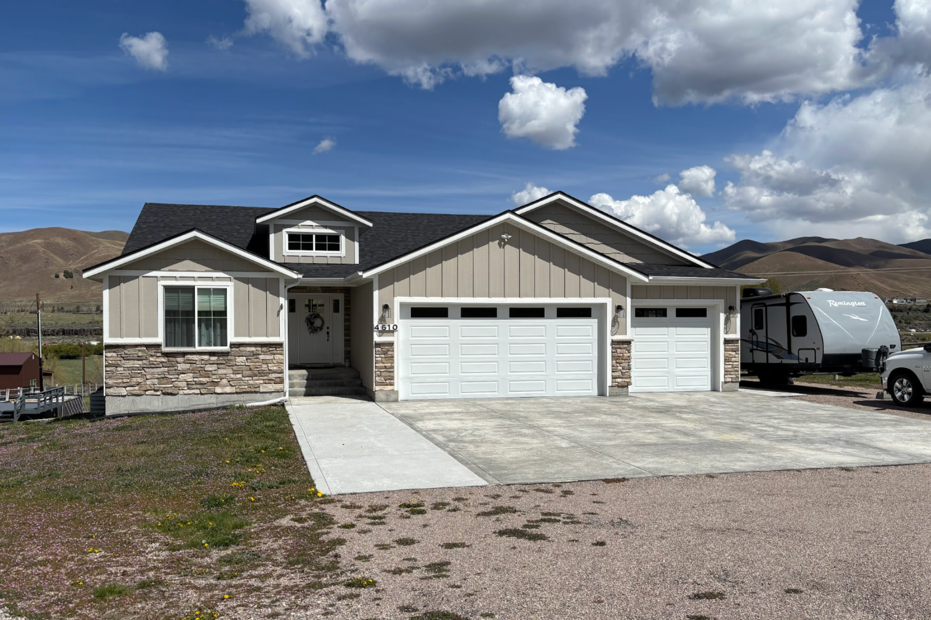 Single-story house with stone accents, two-car garage, and a white van parked beside it under a cloudy sky