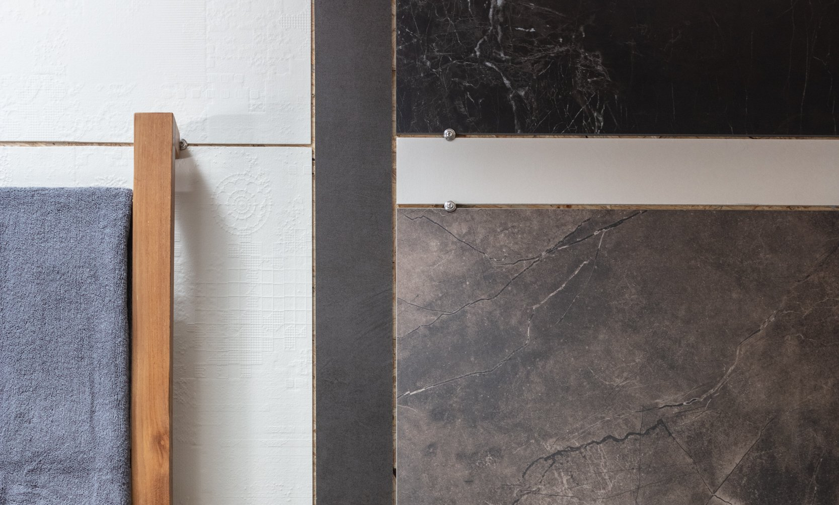 Gros plan sur un mur orné de panneaux de tissu gris, d'une moulure en bois et de carreaux de pierre foncée.
