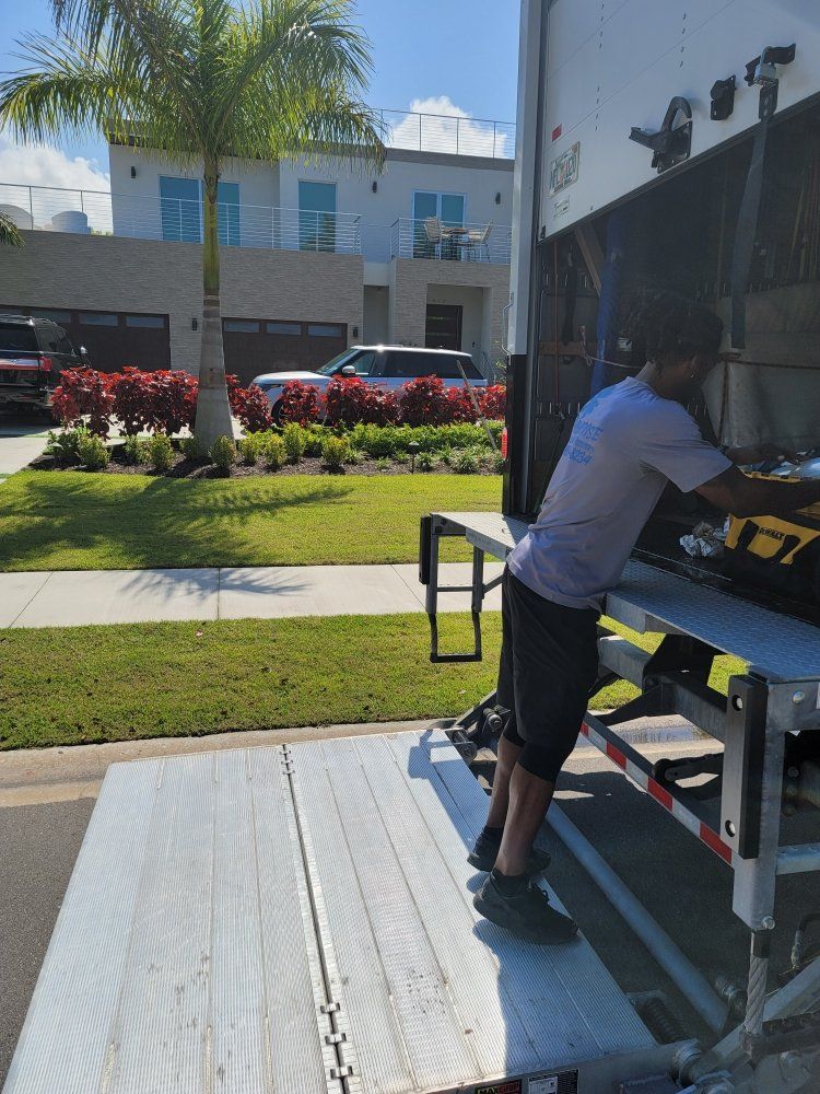 Person loading a black truck from a ramp beside a building on a sunny day