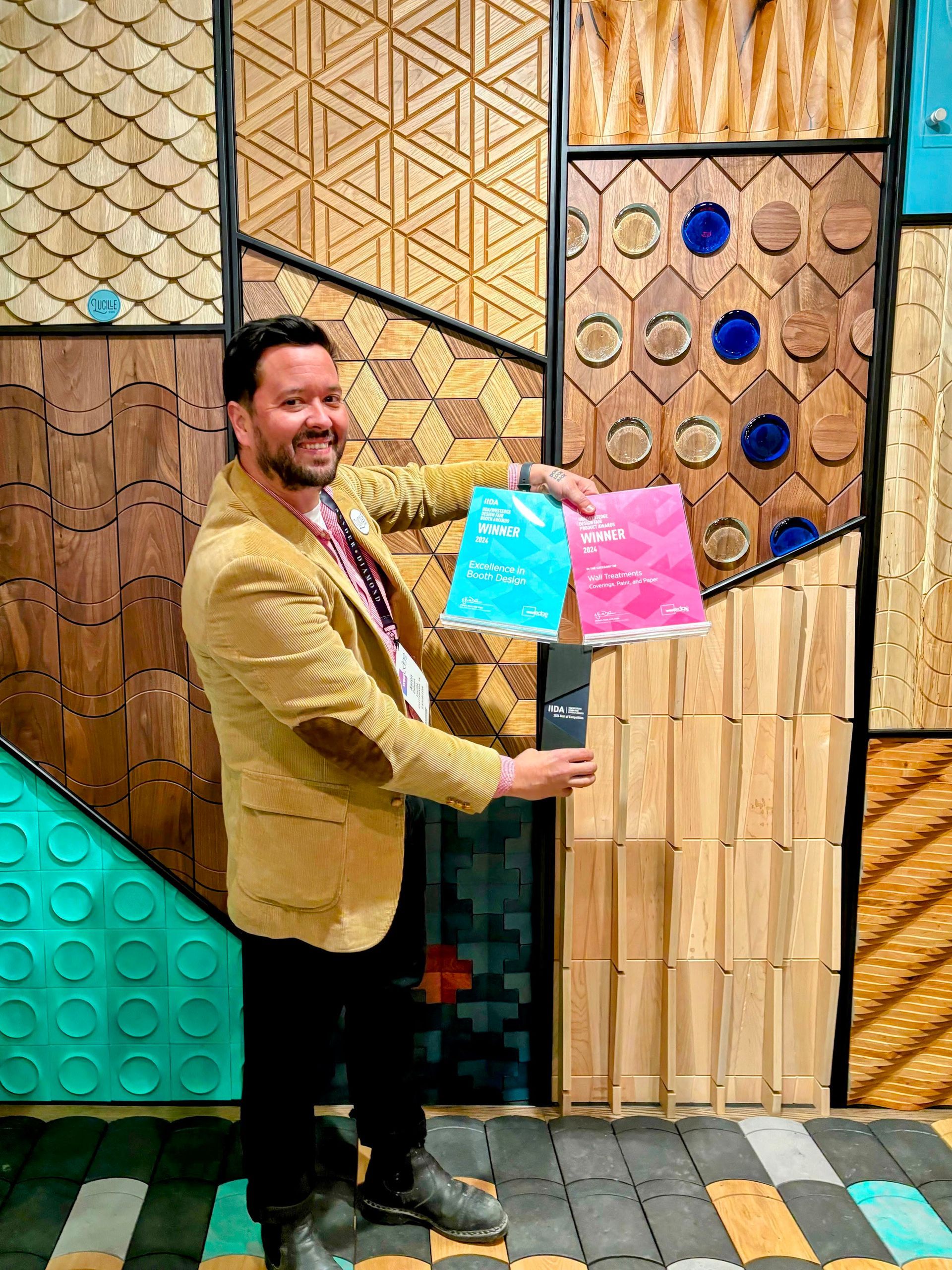 A man is standing in front of a wall holding two bags.