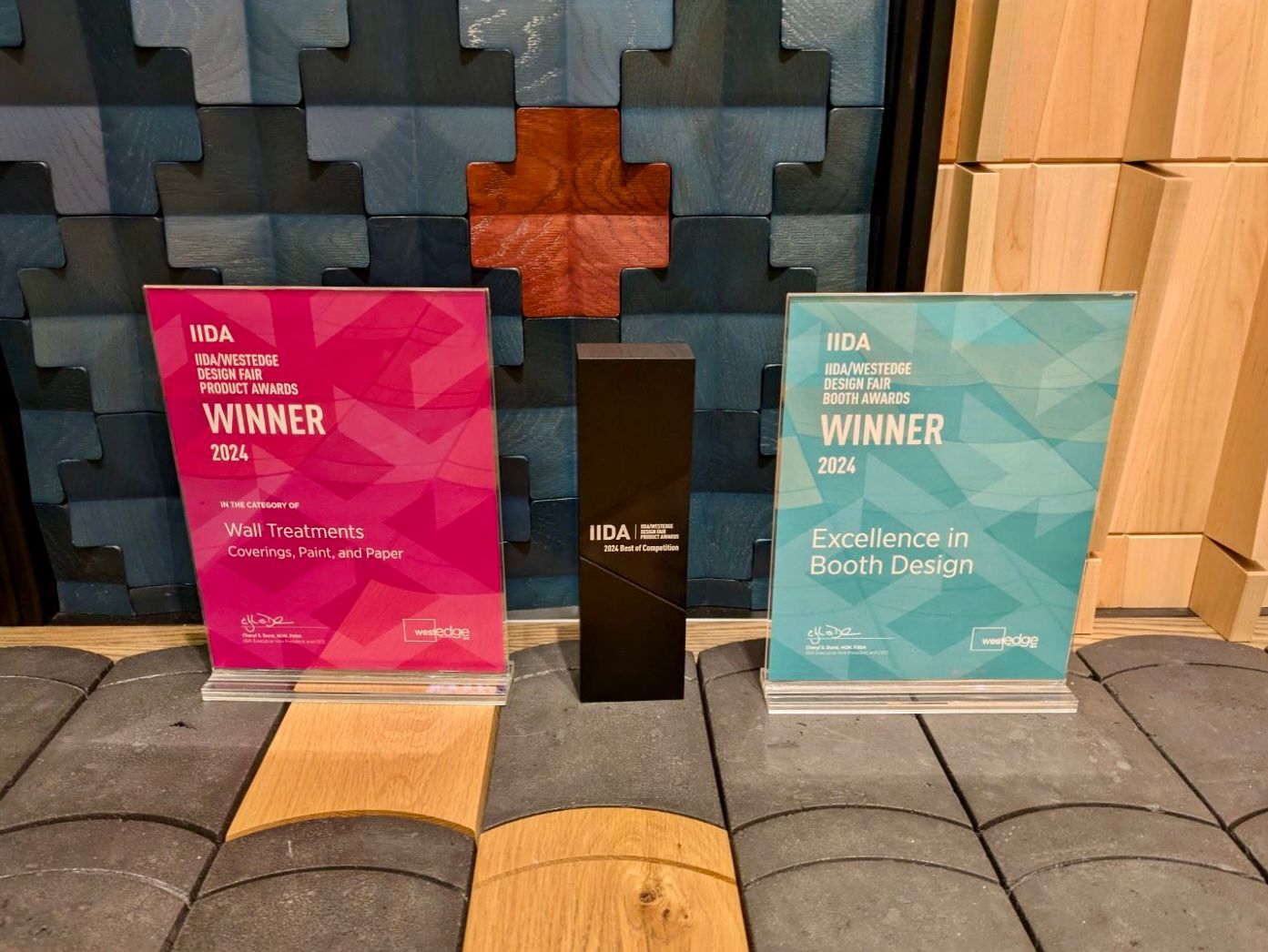 Three awards are sitting on a brick floor in front of a wall.
