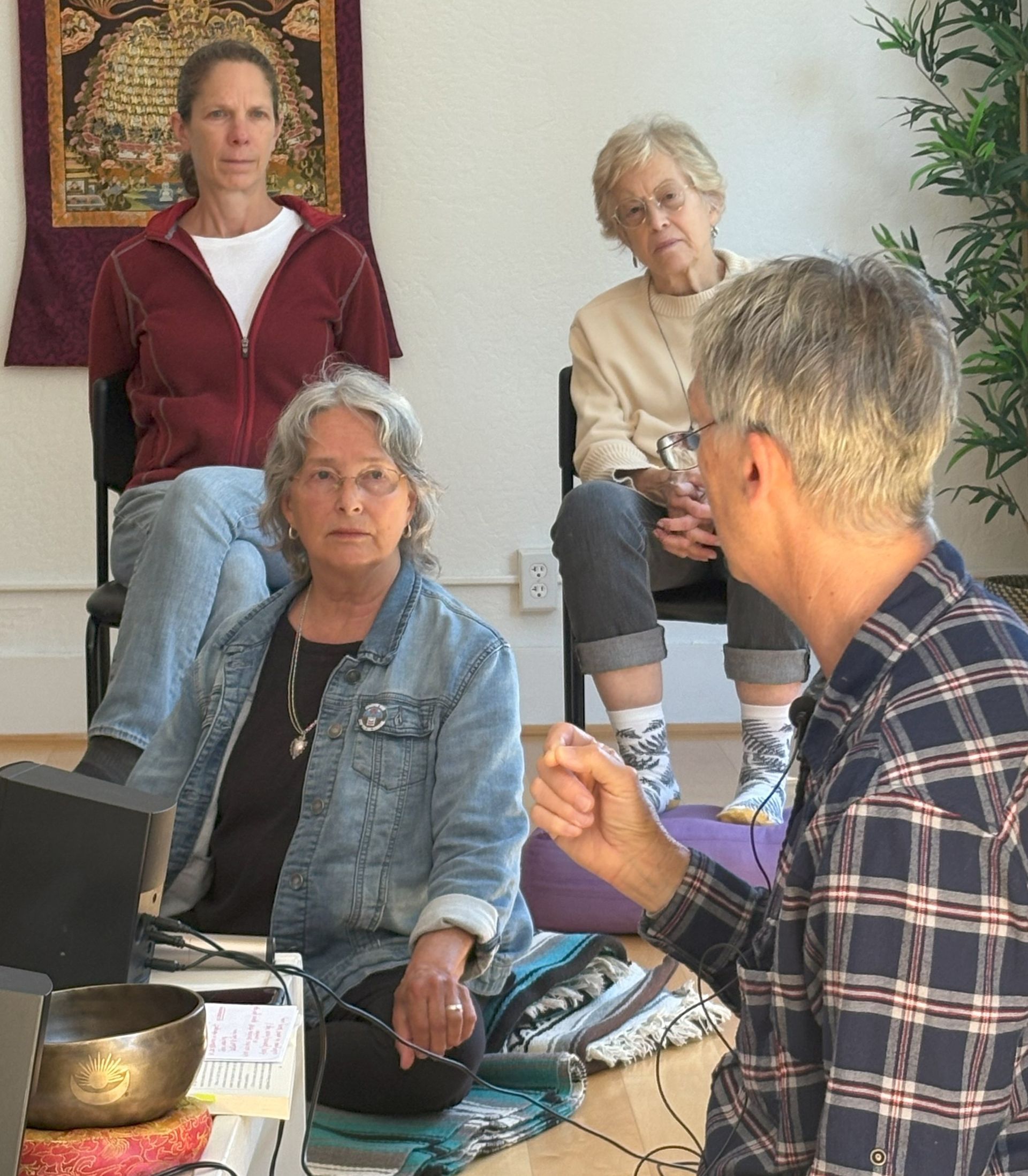 Group of women meditating indoors with eyes closed.