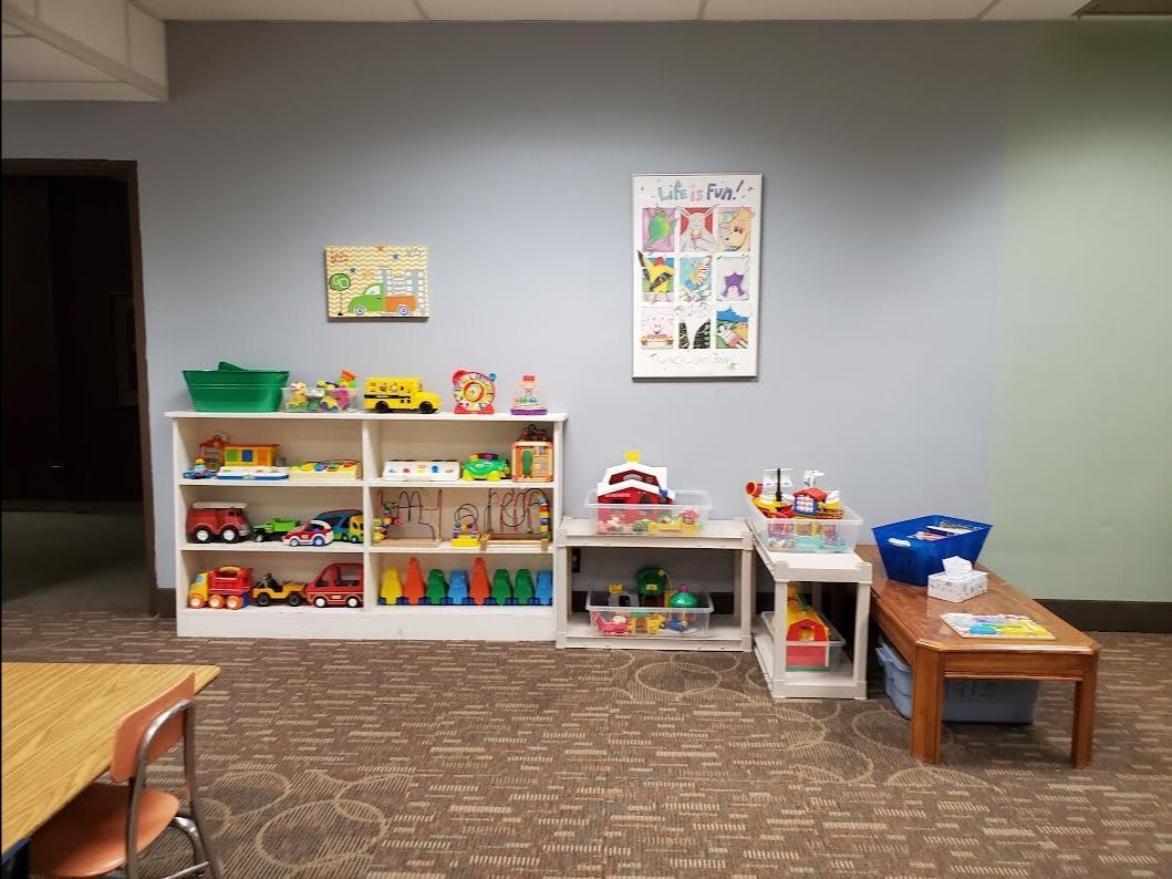 Nursery in the basement at Christ the King, featuring a few shelves and low tables with toys and a child-sized table.