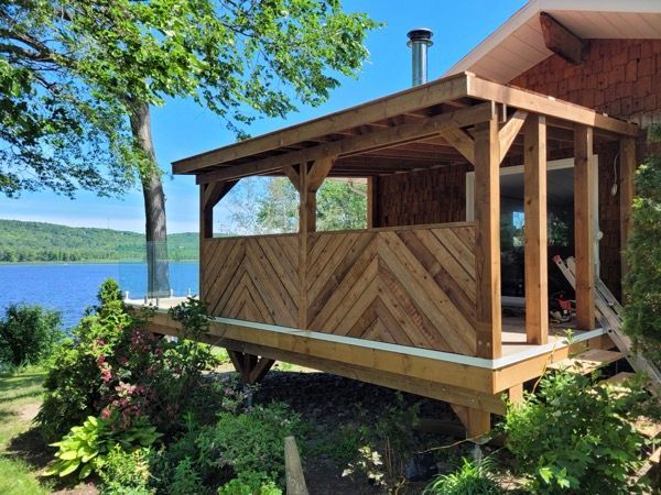 Une maison avec un porche en bois donnant sur un lac.