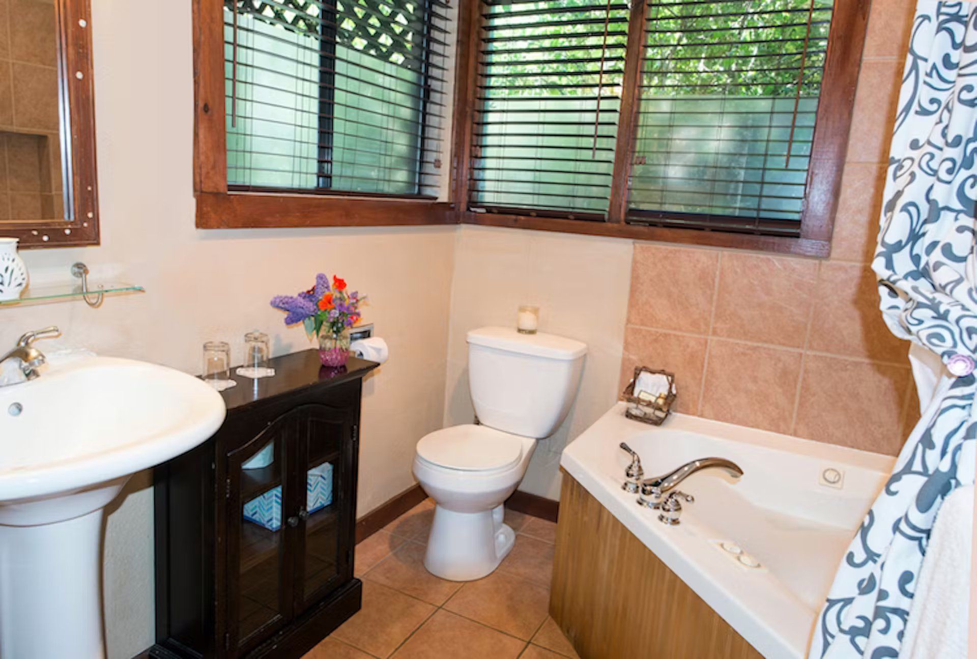 A bathroom with a toilet , sink , tub and window.