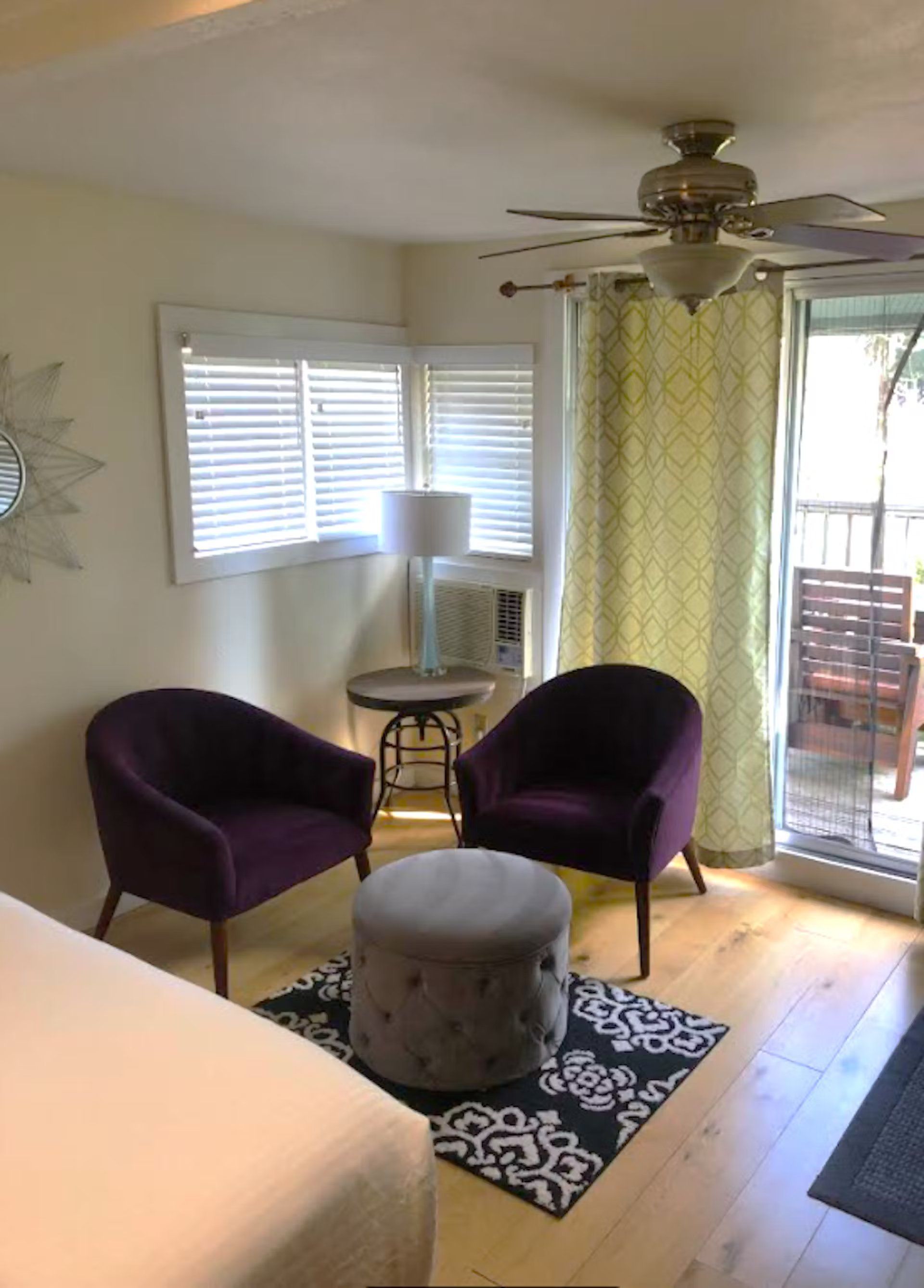 A living room with two purple chairs and a ceiling fan.