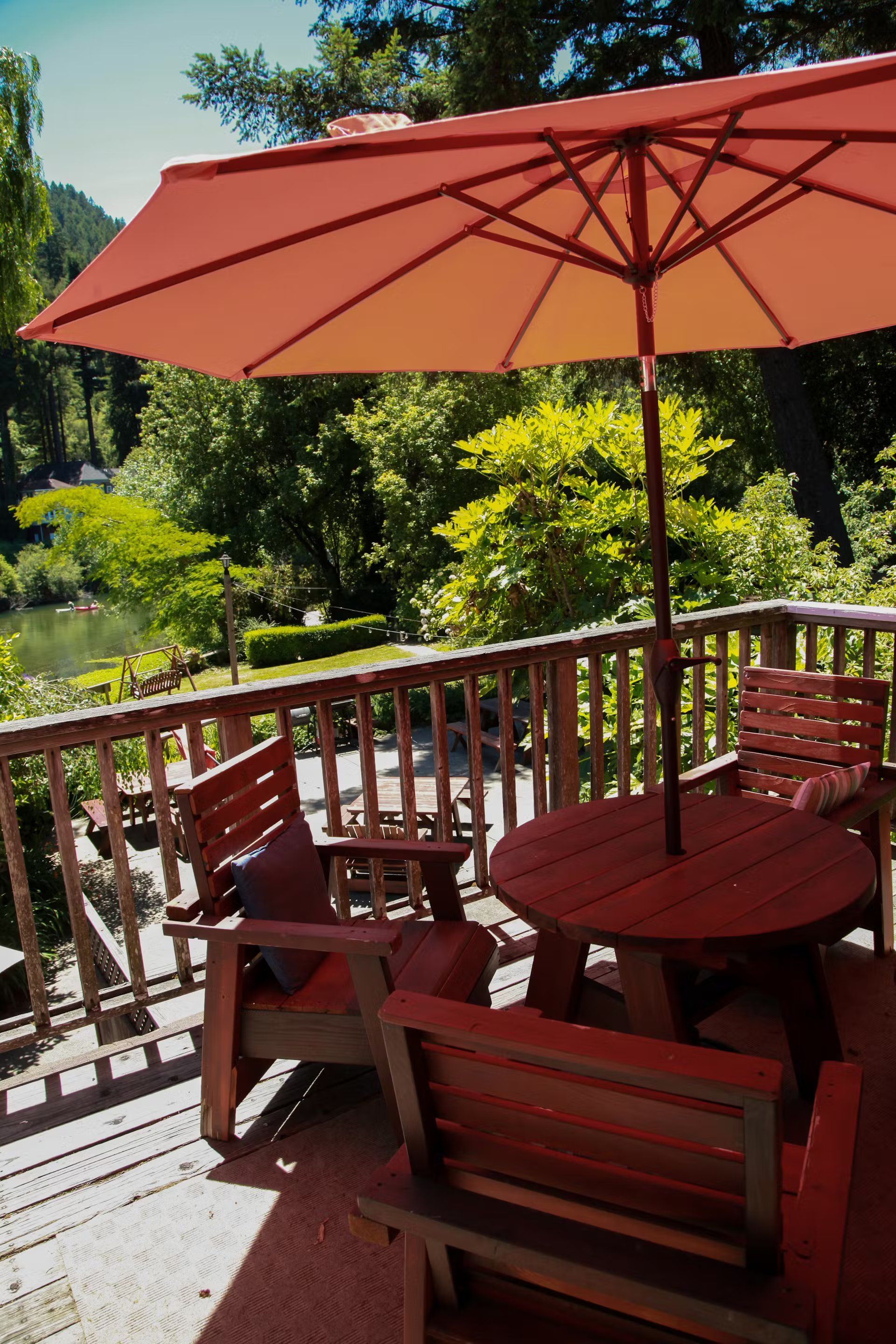 A deck with a table and chairs under an orange umbrella