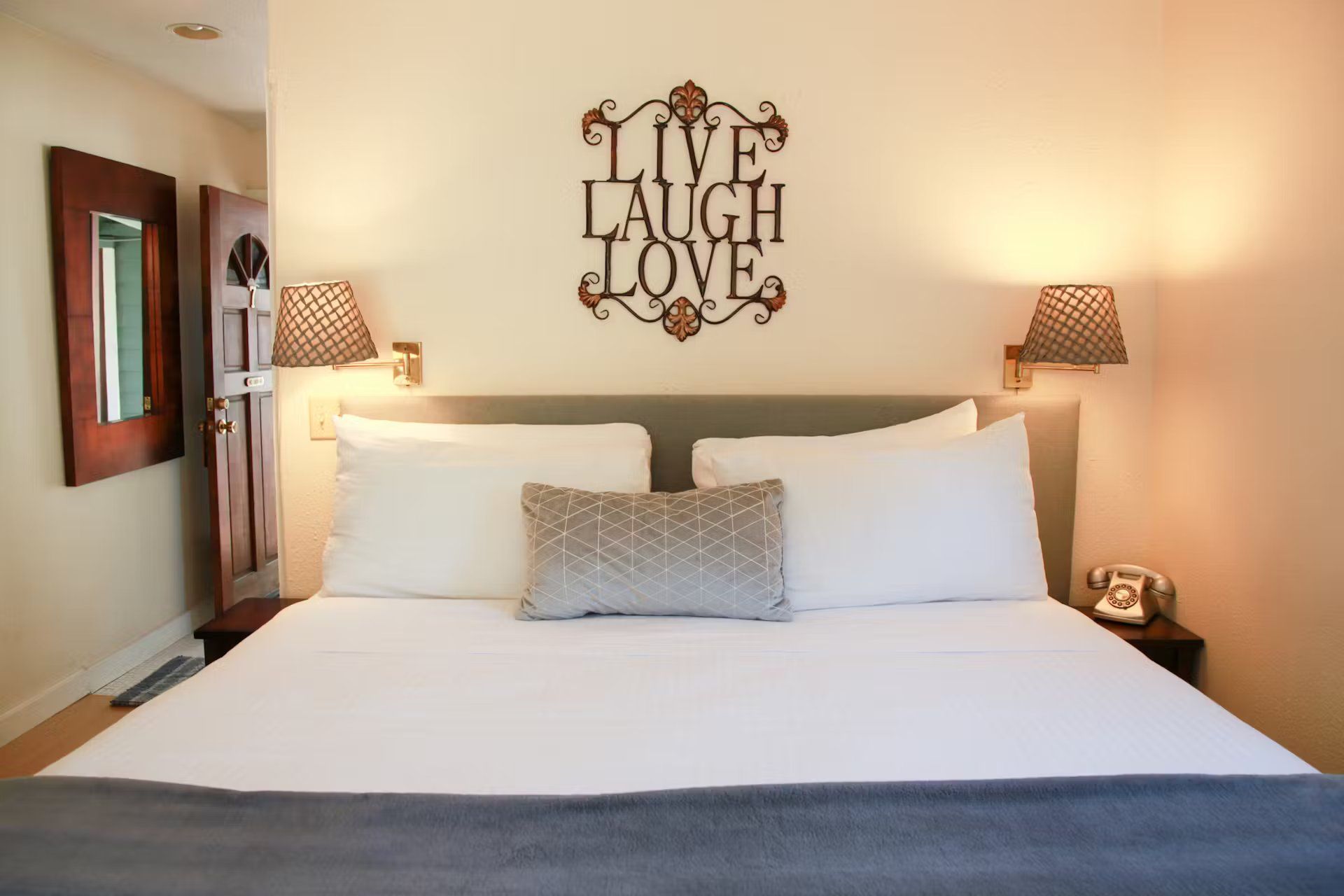 A bed with a sign on the wall that says live laugh love
