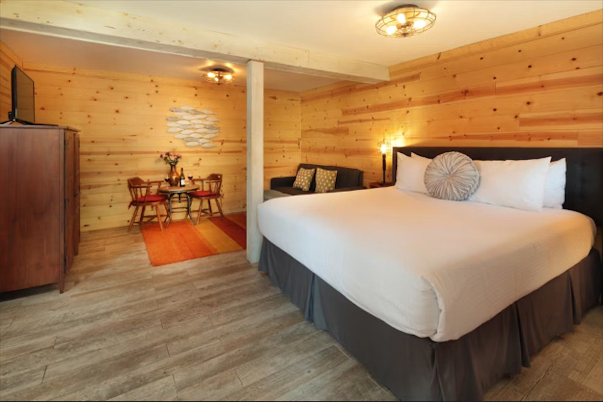 A hotel room with a king size bed , couch , table and chairs.