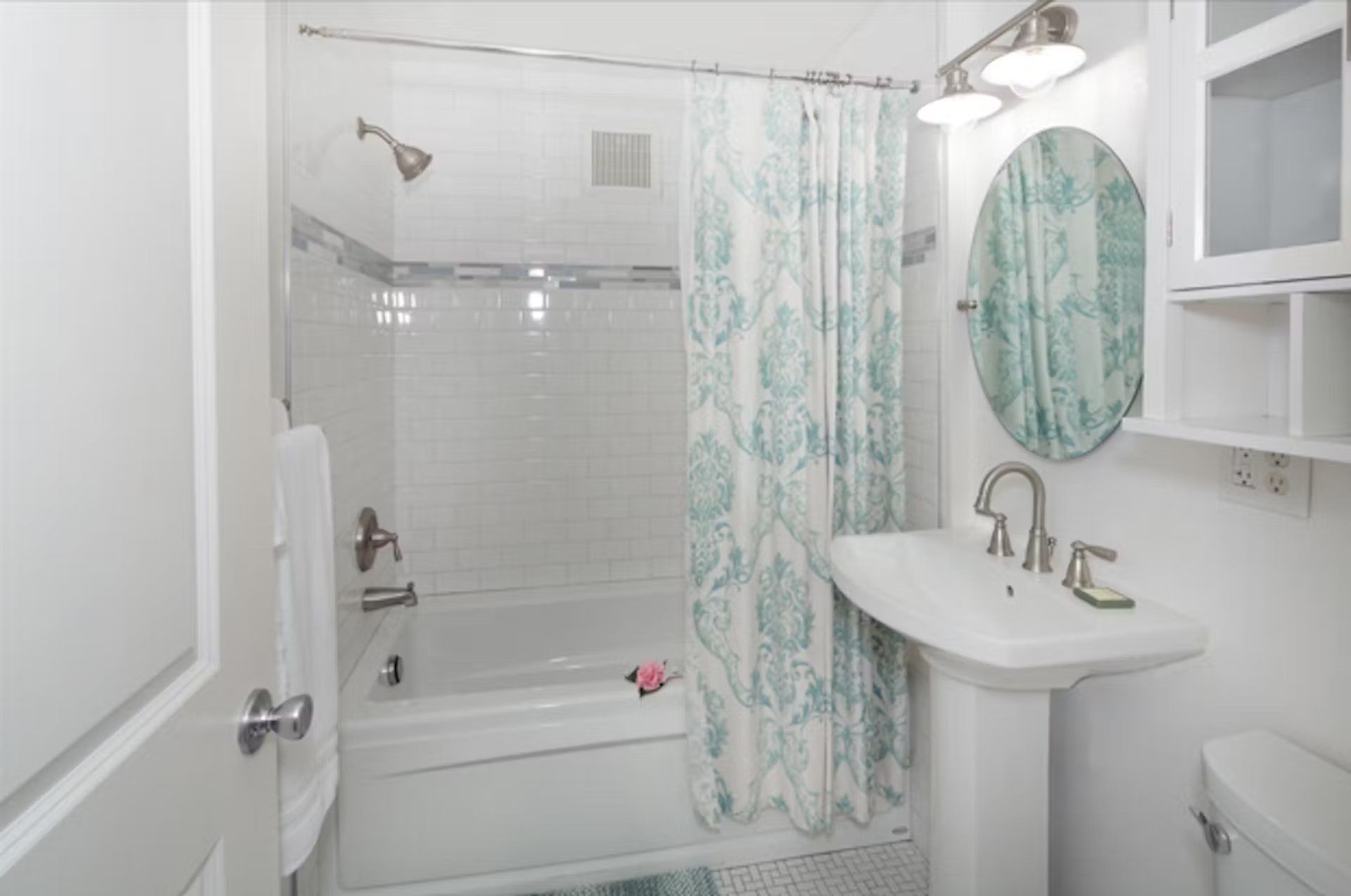 A bathroom with a bathtub , sink , mirror and shower curtain.