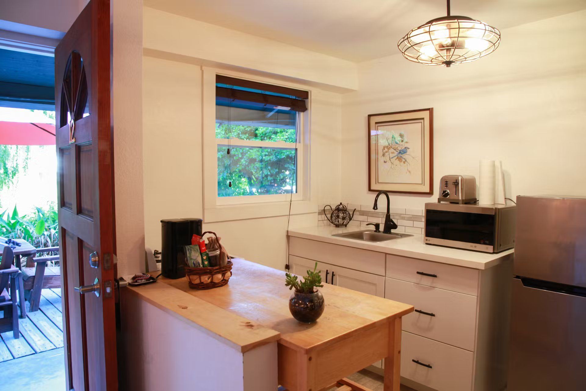 A kitchen with a table , refrigerator , microwave and sink.