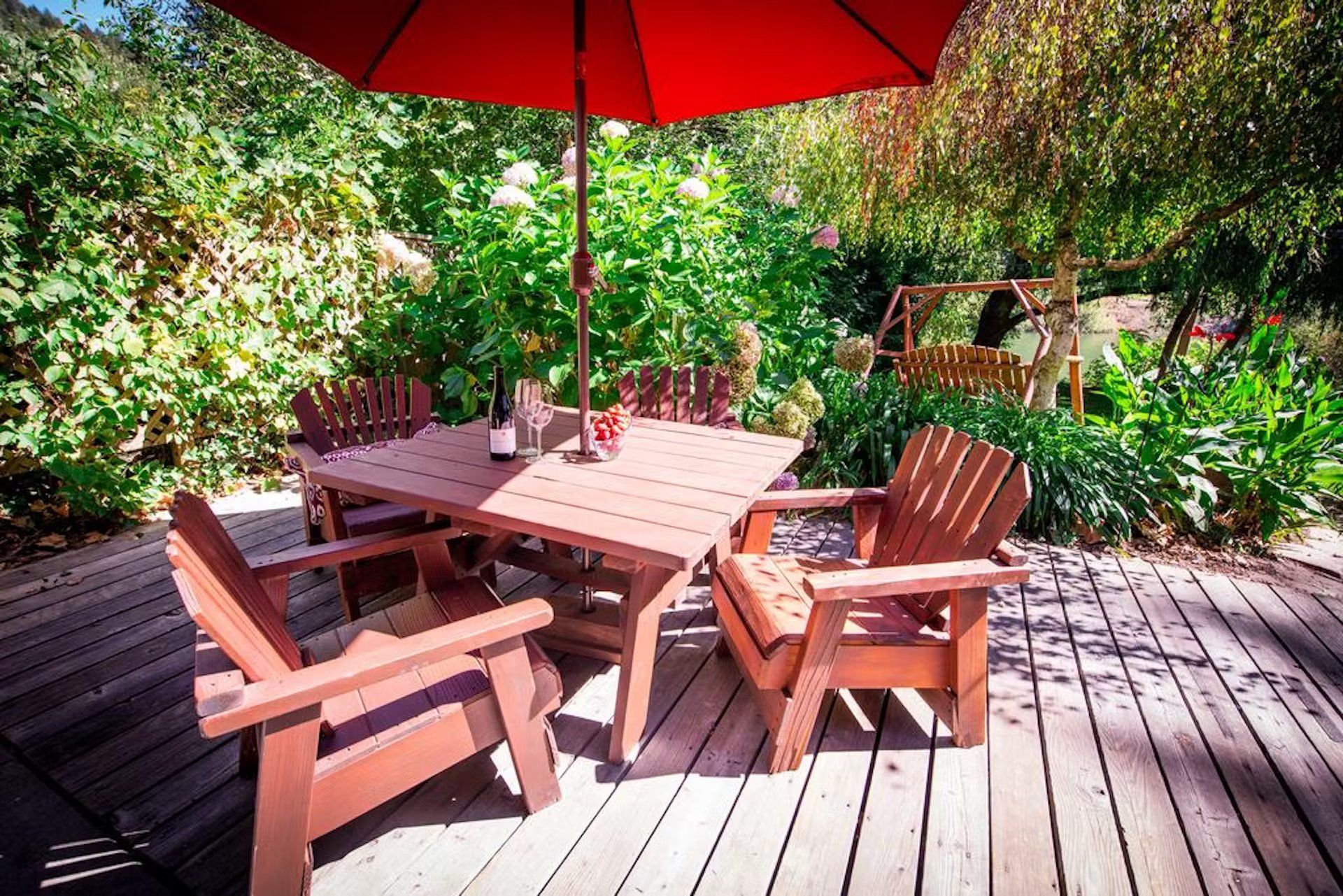 A wooden deck with a table and chairs under an umbrella.