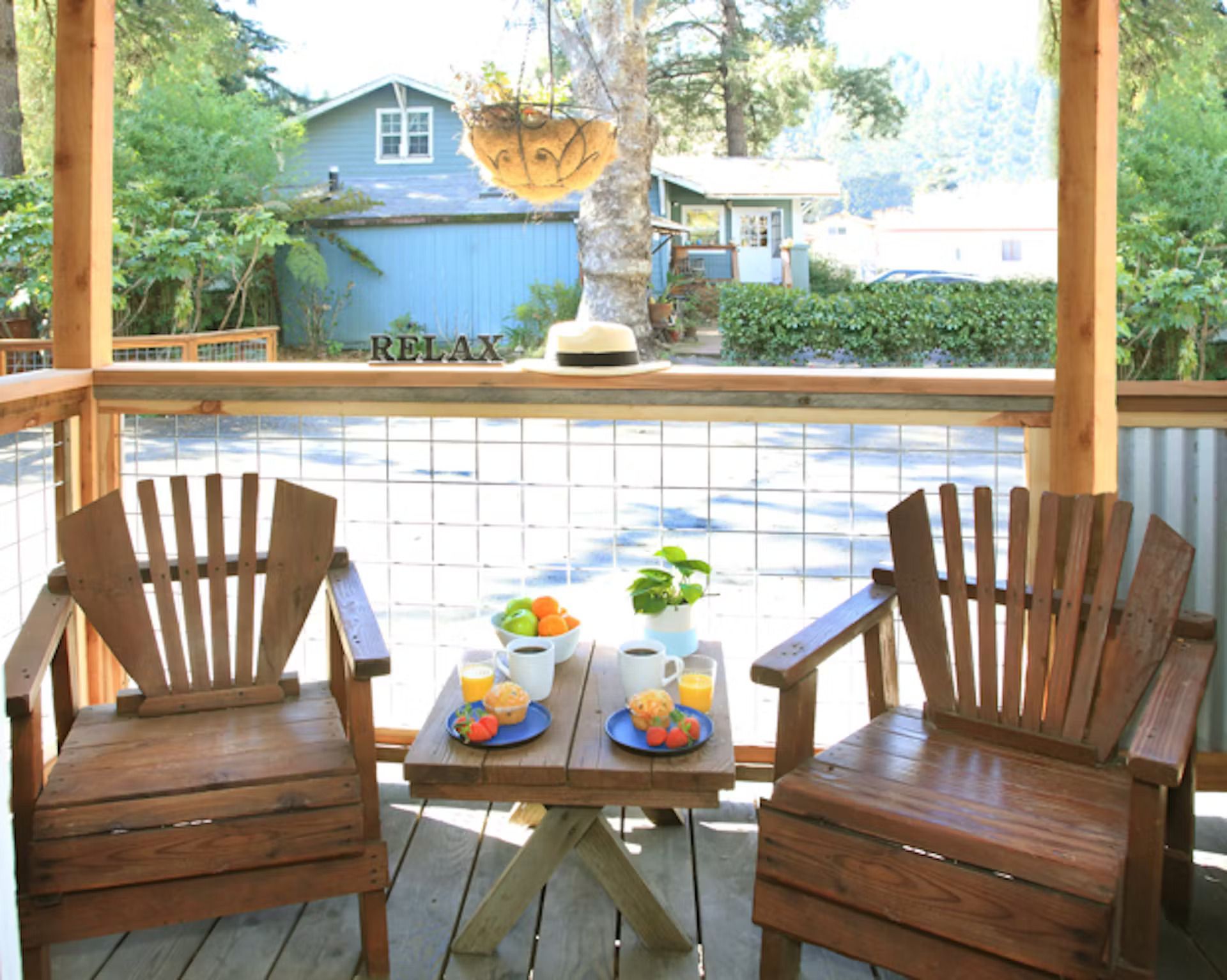Two chairs and a table on a porch with a sign that says relax