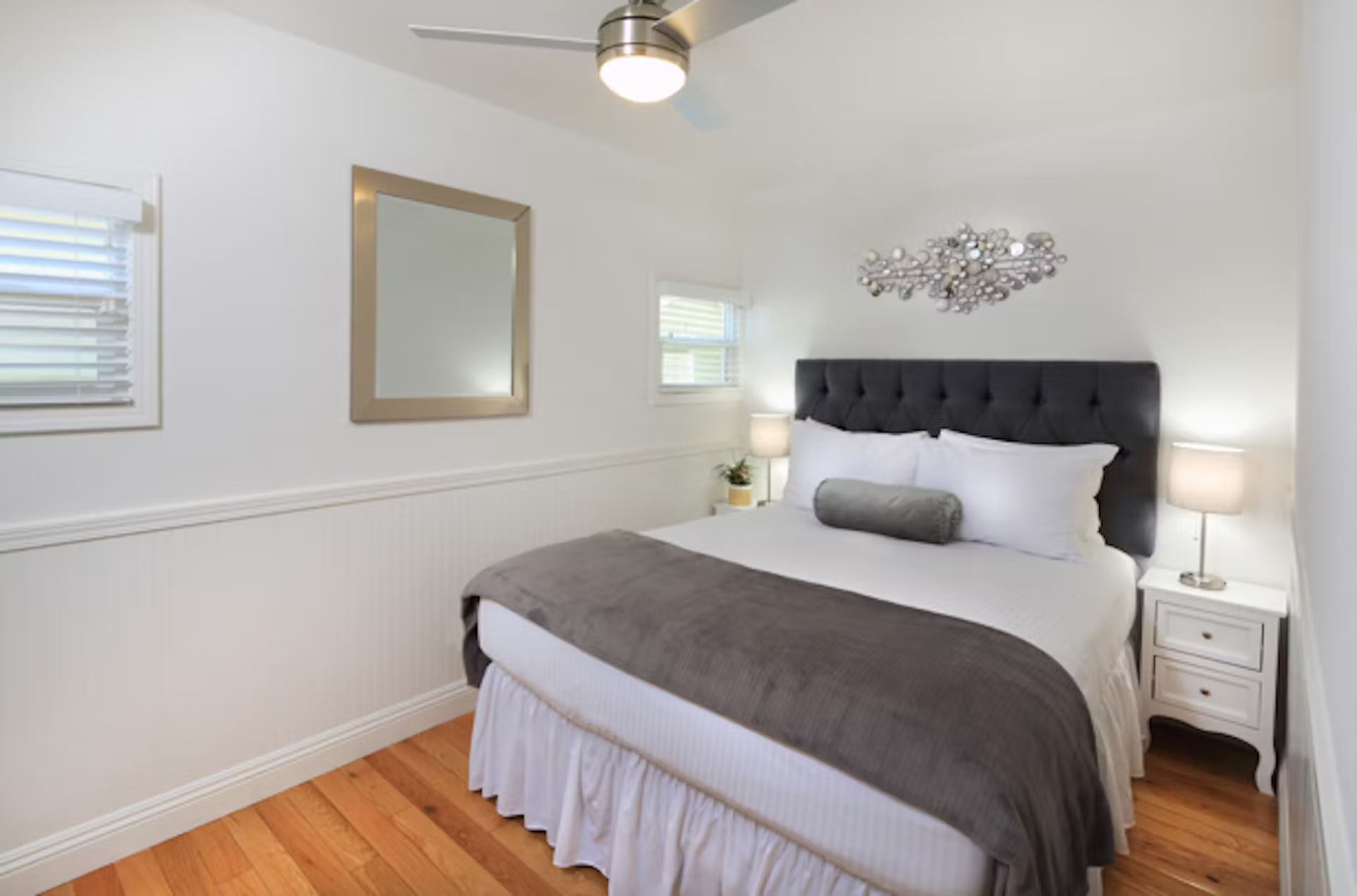 A bedroom with a bed , nightstand , mirror and ceiling fan.