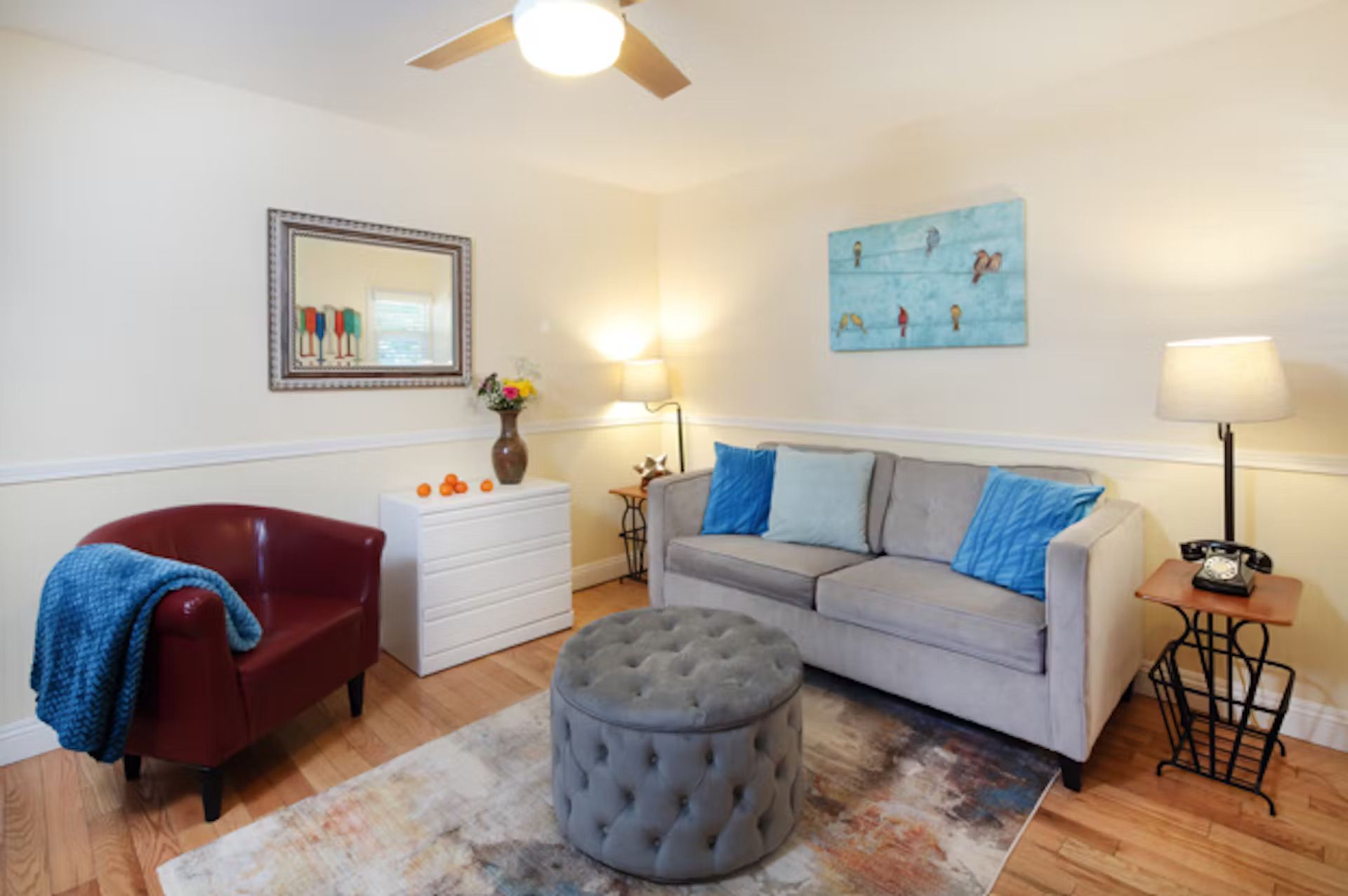 A living room with a couch , chair , ottoman and ceiling fan.