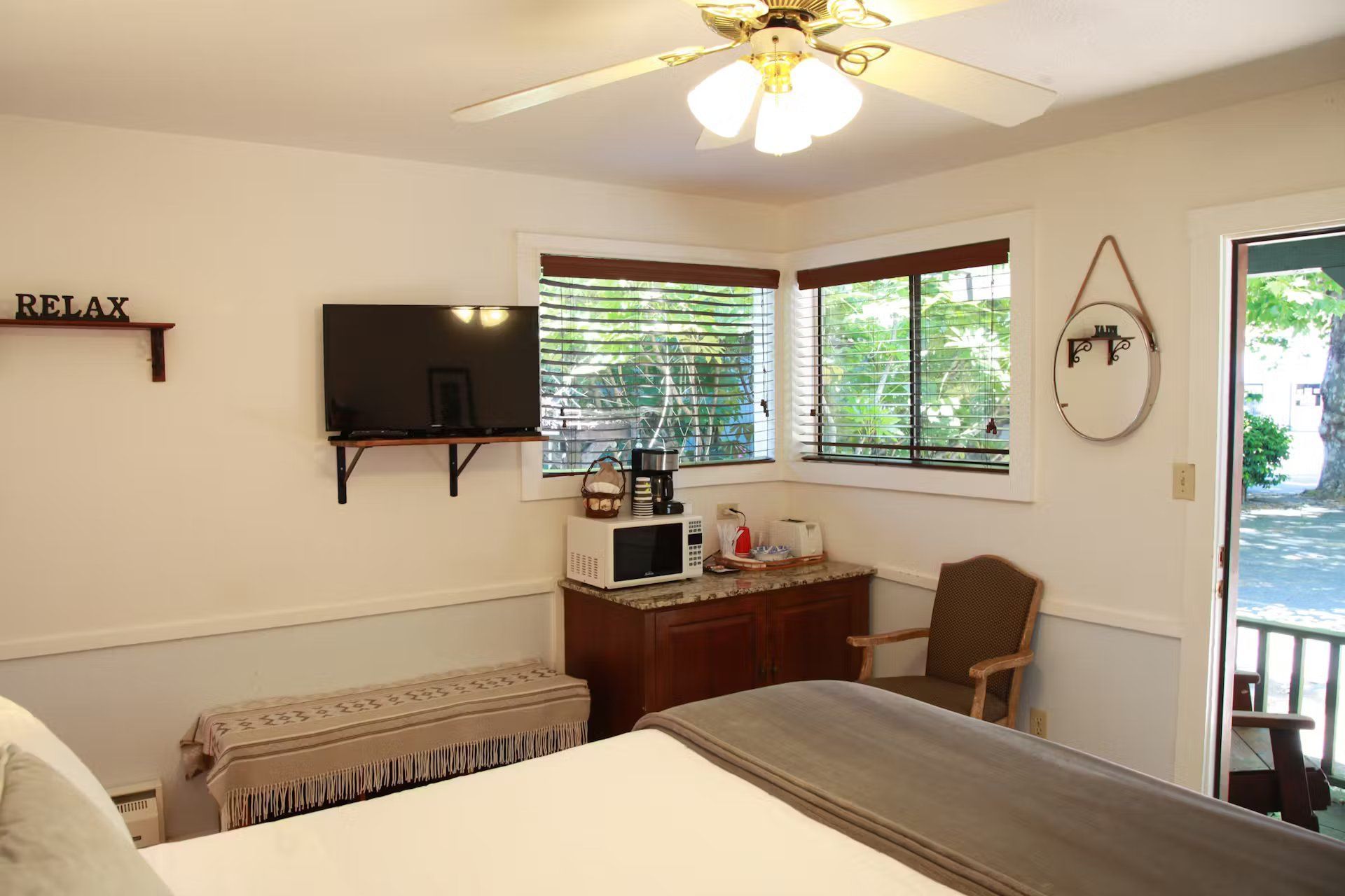 A bedroom with a bed , television , microwave and chair.