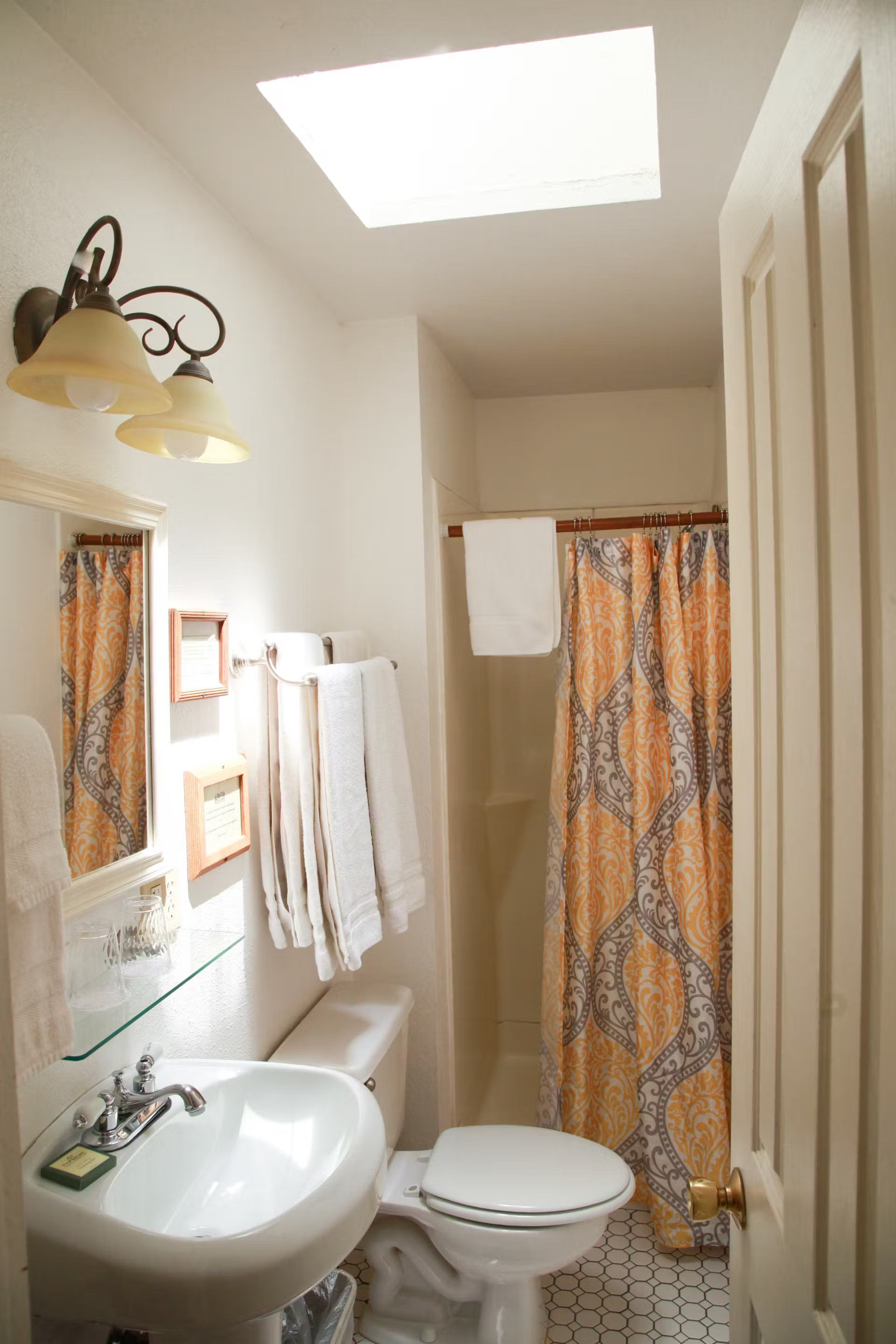 A bathroom with a sink , toilet , shower and skylight