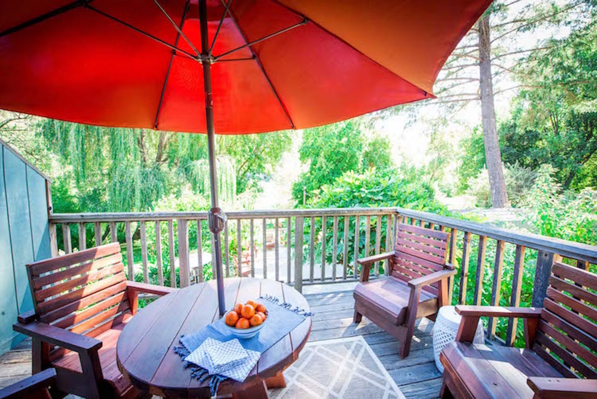 A wooden deck with a table and chairs under an umbrella.