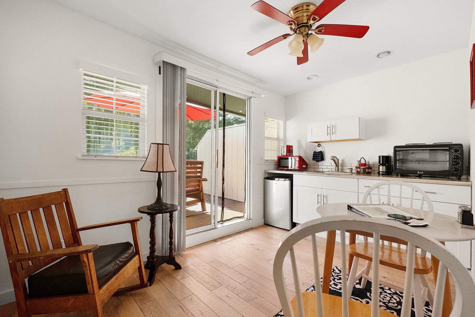 A living room with a ceiling fan and a sliding glass door leading to a patio.
