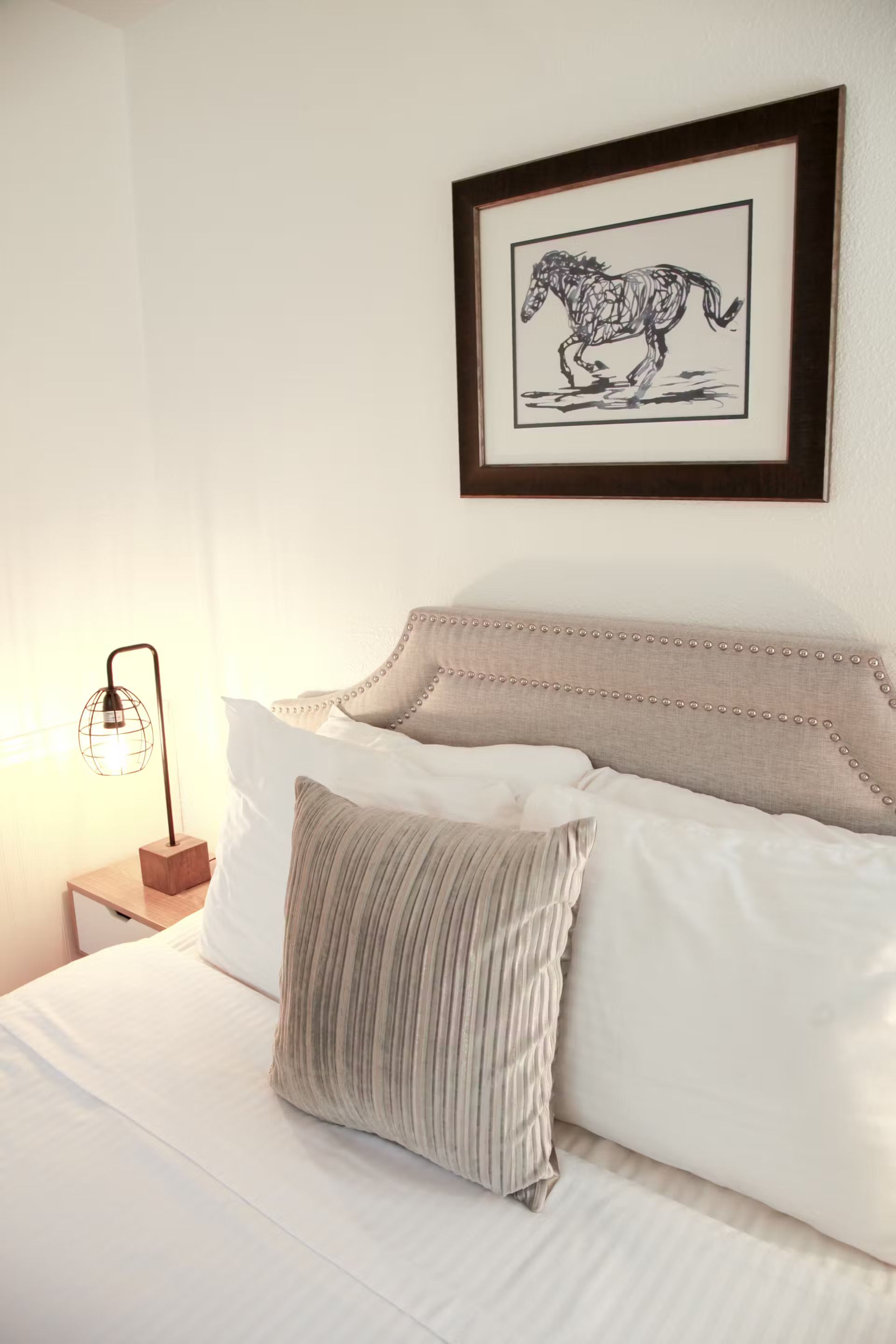 There is a picture of a horse on the wall above the bed.