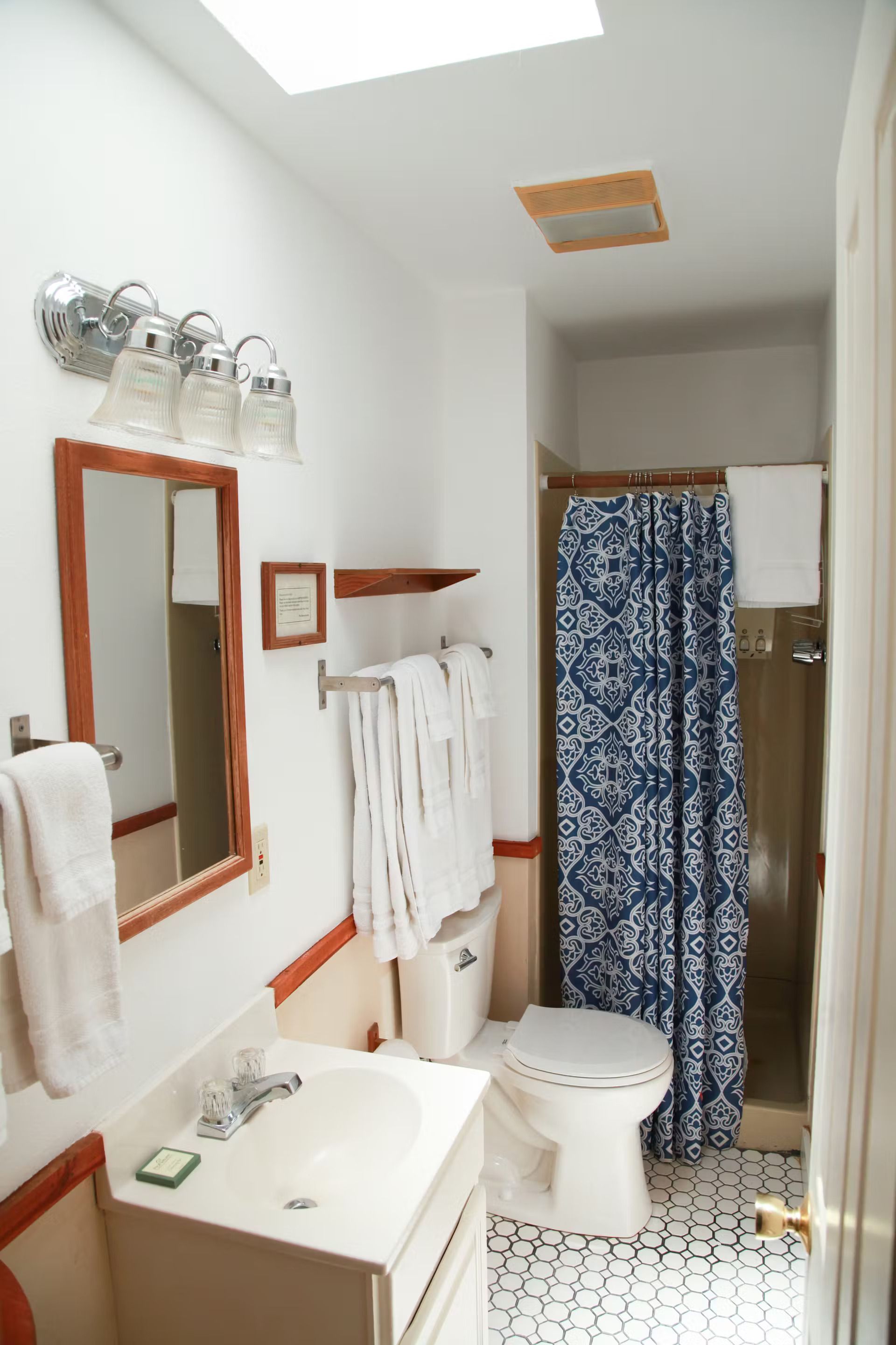 A bathroom with a toilet , sink , mirror and shower curtain