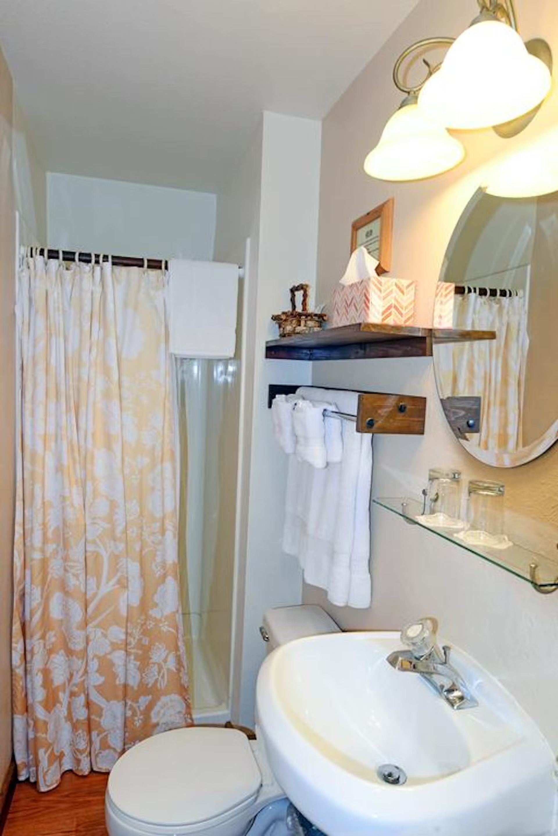 A bathroom with a toilet , sink , mirror and shower curtain