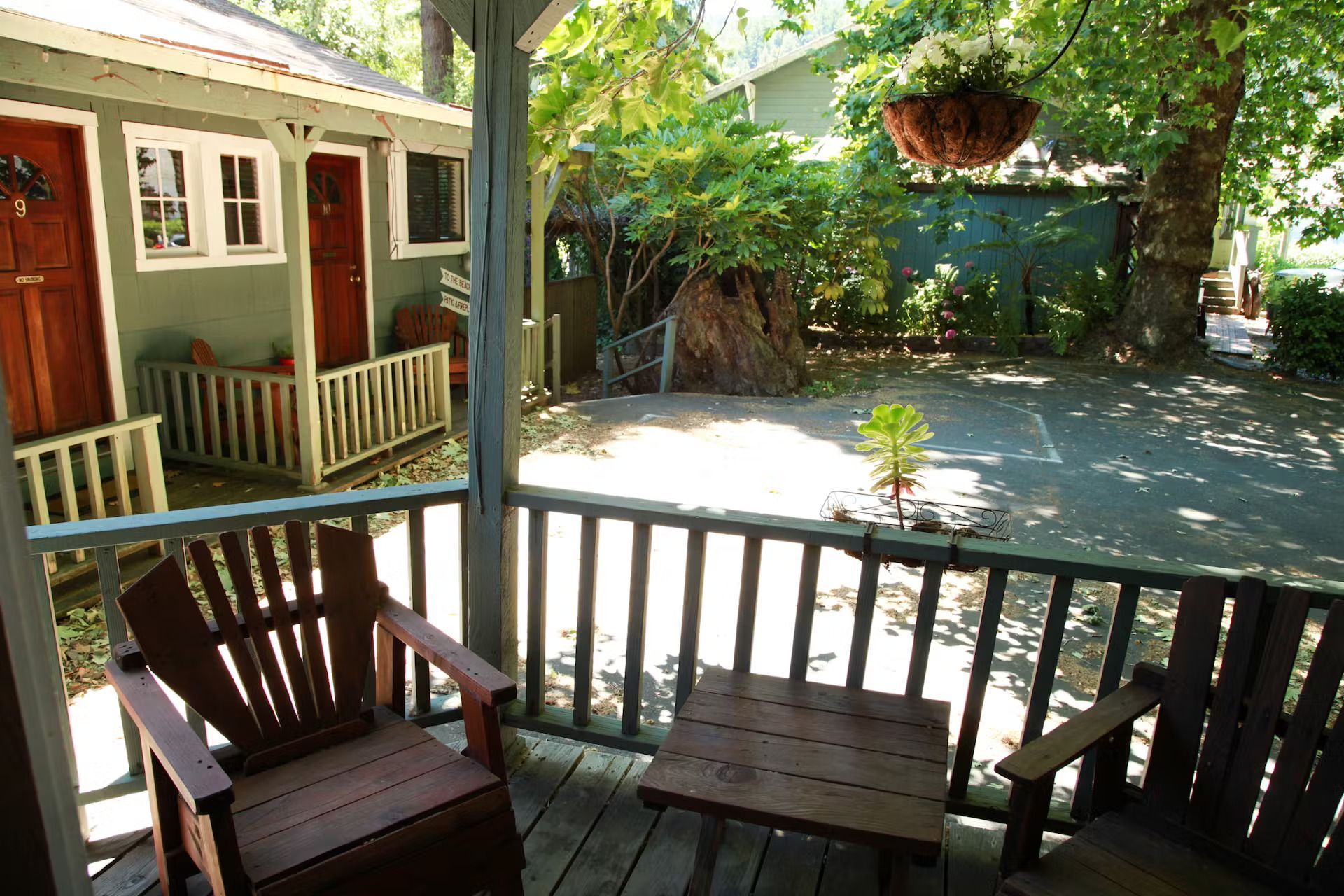Two chairs and a table on a porch with a house in the background