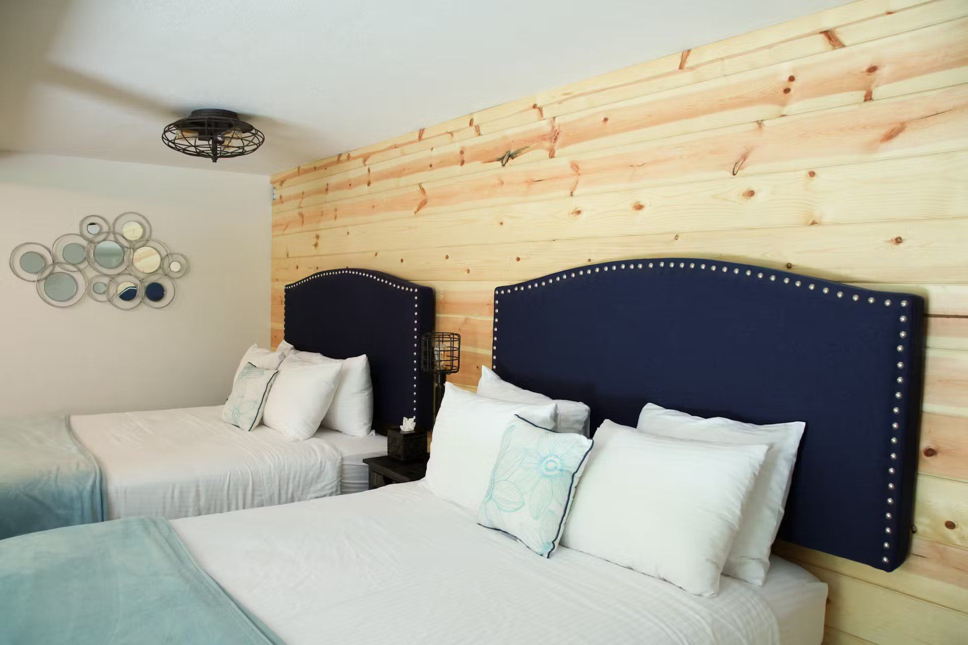 A hotel room with two beds and a wooden wall.
