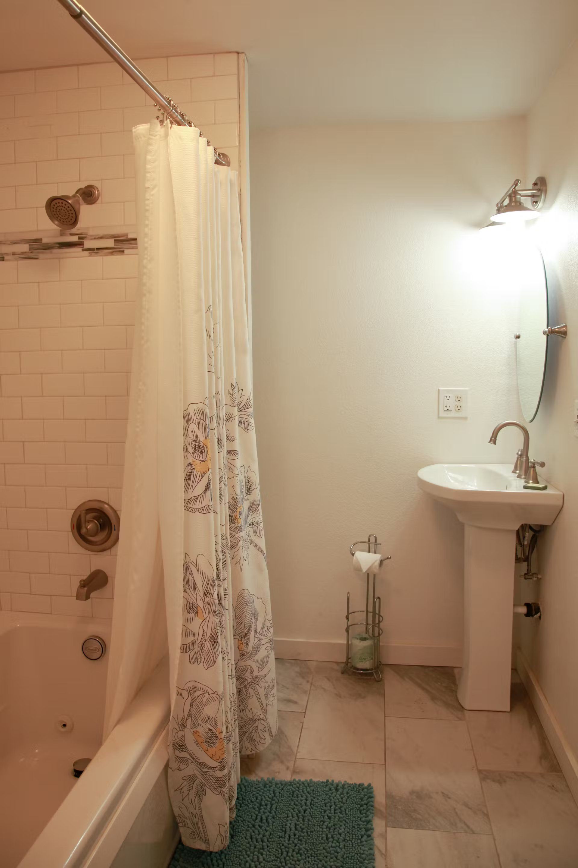 A bathroom with a sink , bathtub , shower curtain and mirror.