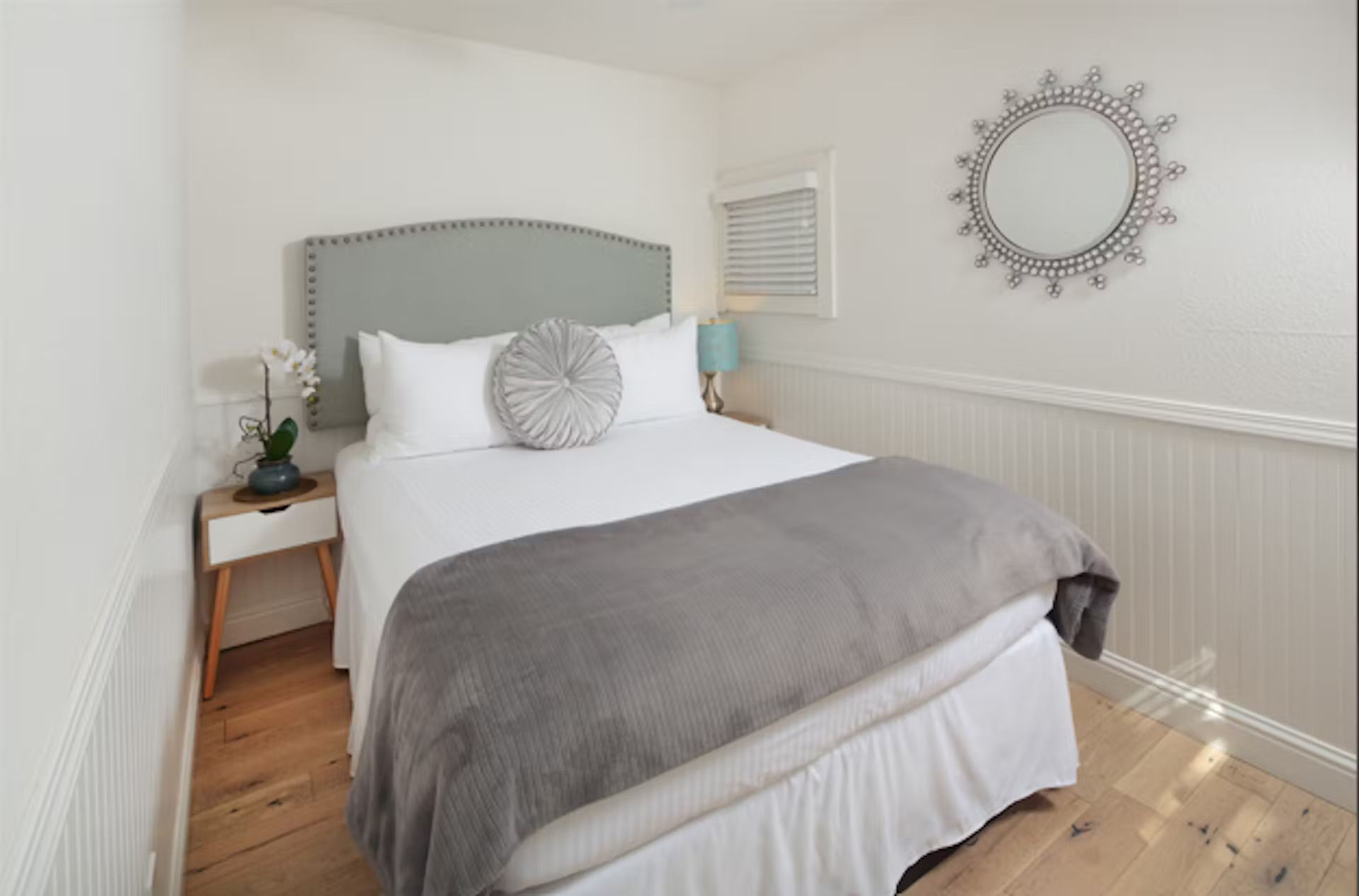 A bedroom with a bed and a mirror on the wall.