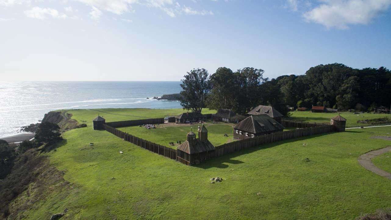 An aerial view of a castle on a hill overlooking the ocean.