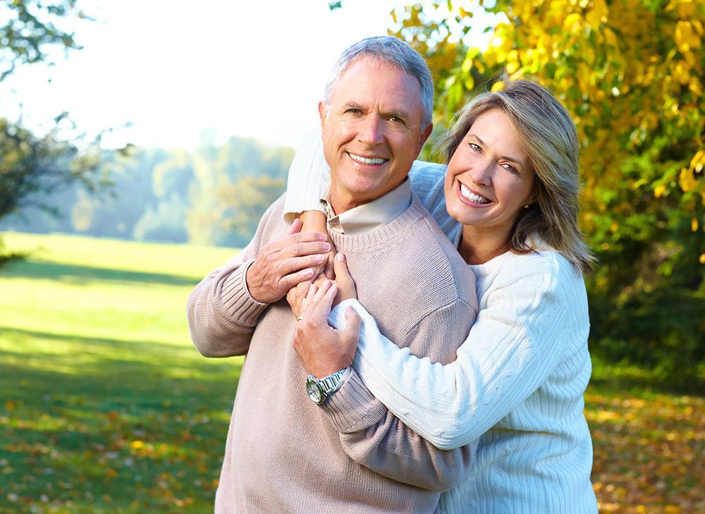 White elderly couple embracing each other at the park