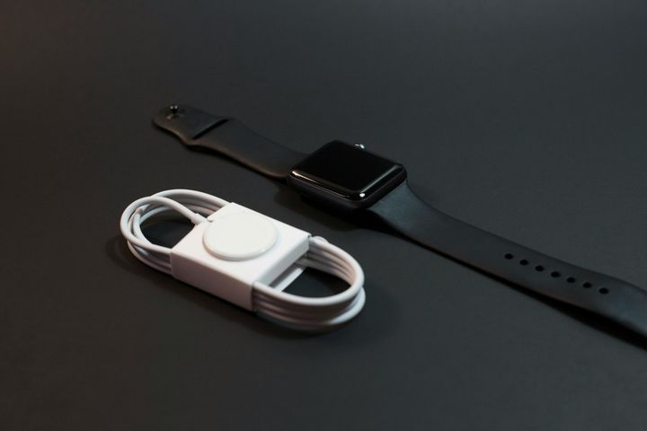 Apple Watch with charging cable on a black surface.