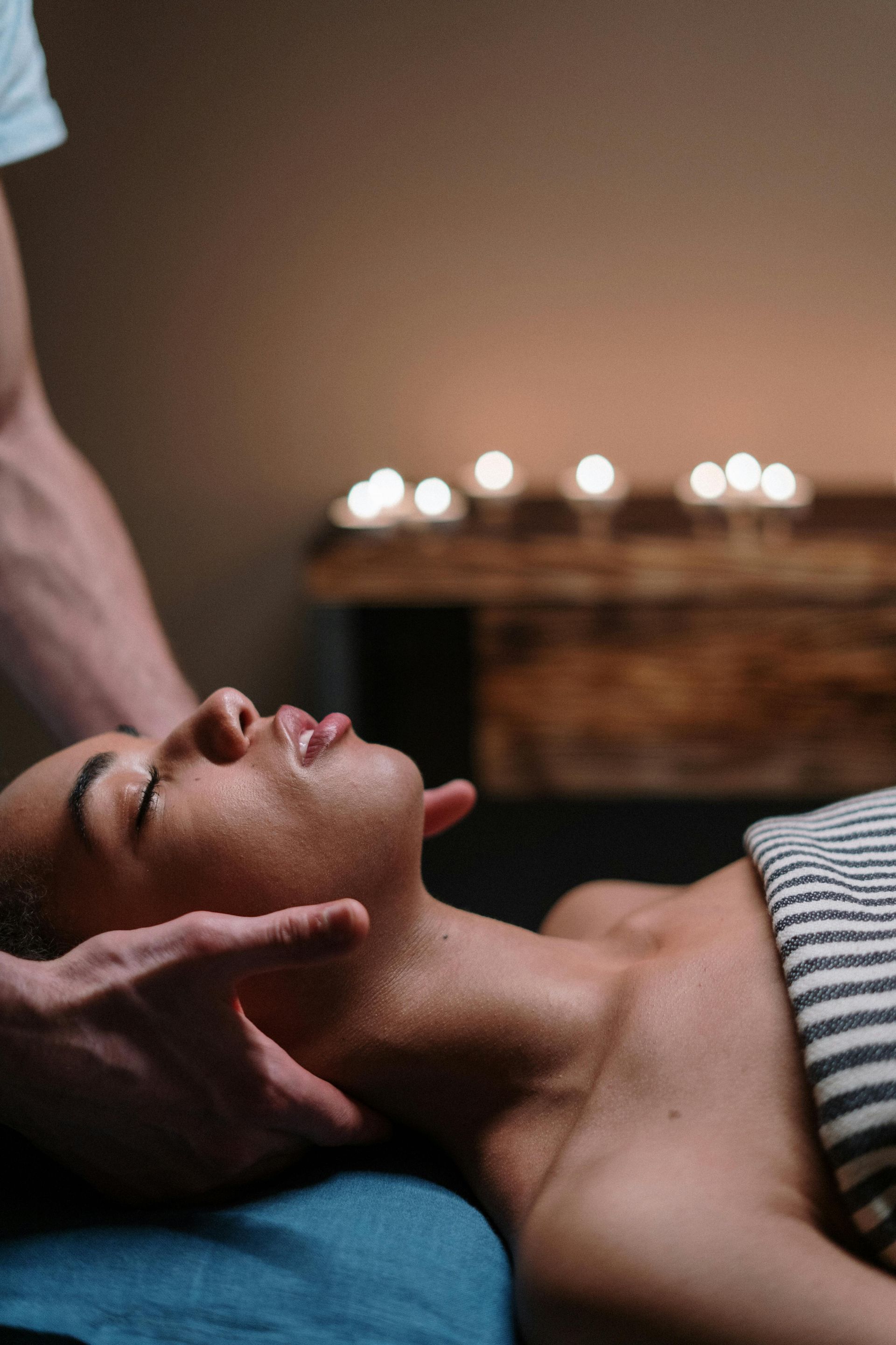 Person receiving neck massage. Candles in background.