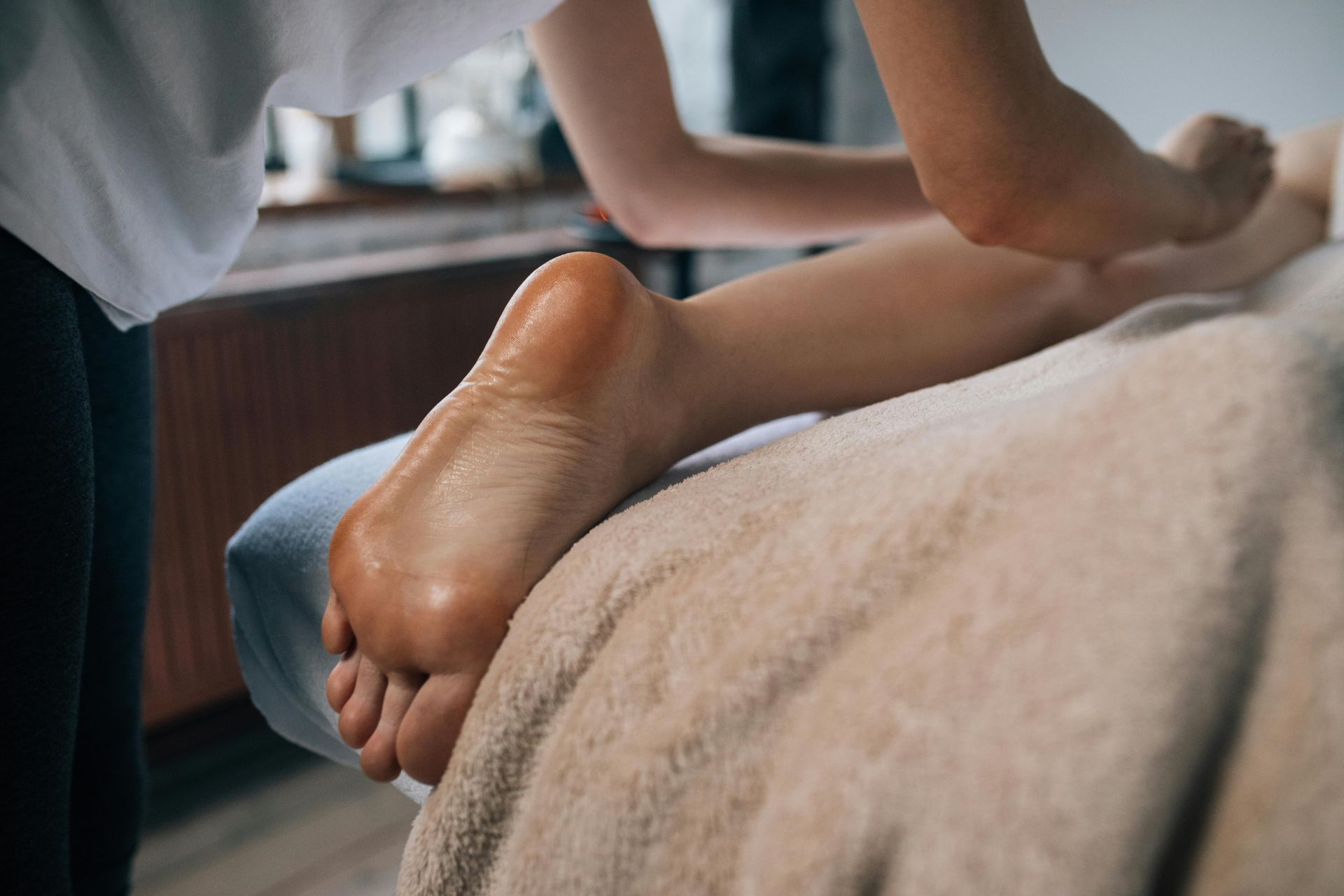 A person receiving a foot massage; legs and feet on a massage table, hands working the muscles.