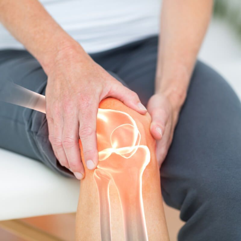 Person holding knee, highlighting the bones with red and white overlay, indicating pain.