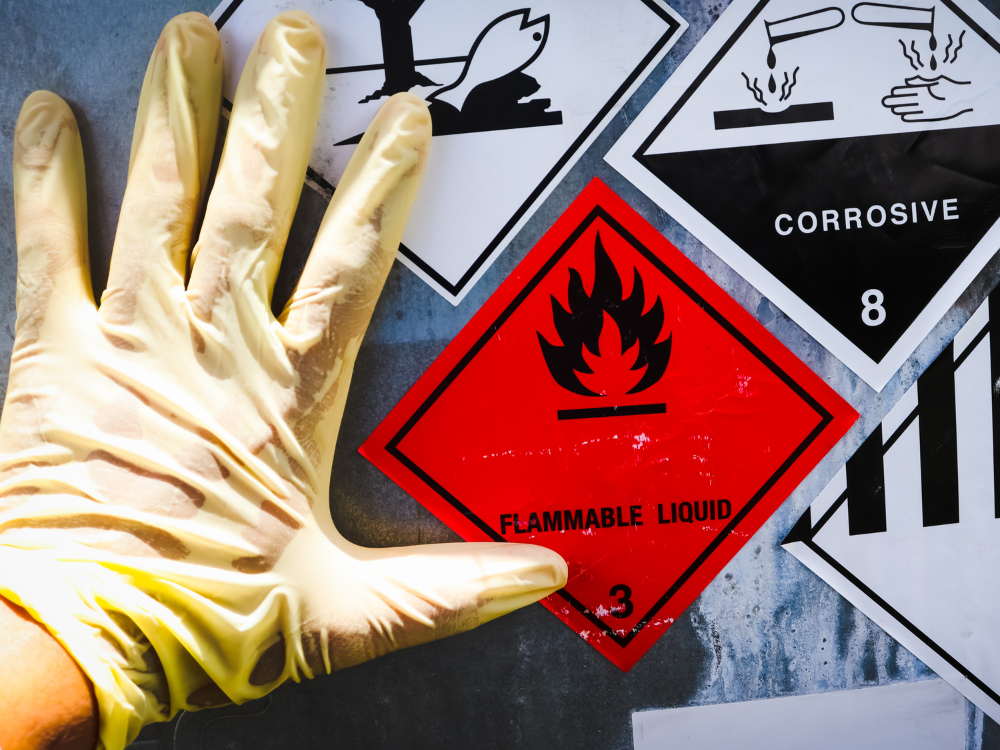 A hand within a glove handling flammable and corrosive material.
