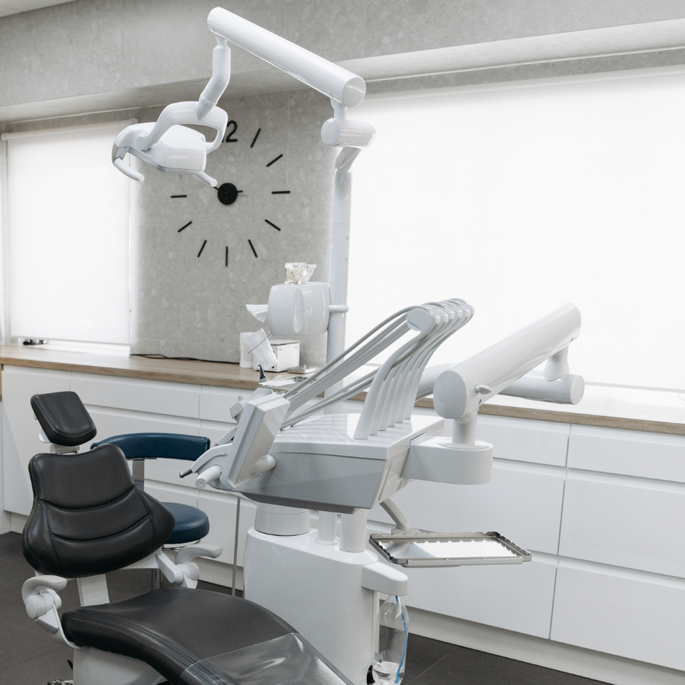 A dental office with a clock on the wall and a chair.