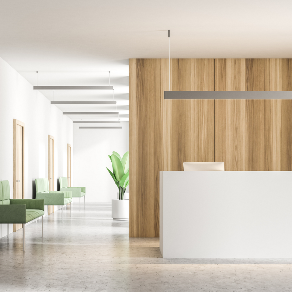 A reception area in a hospital with a wooden wall and a white counter.