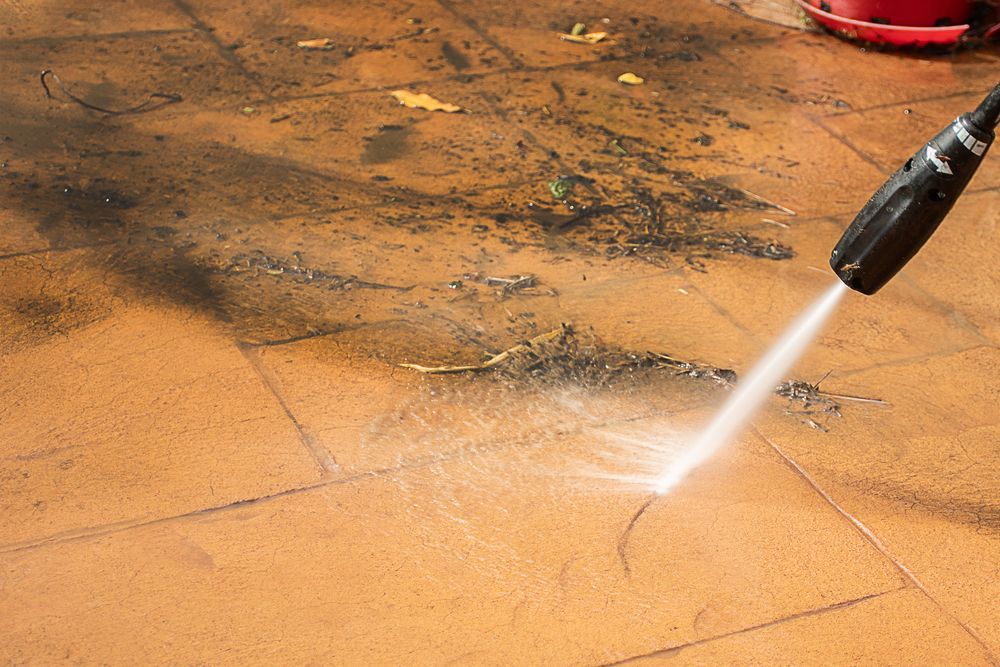 Pressure washer spraying water on a dirty orange tiled floor
