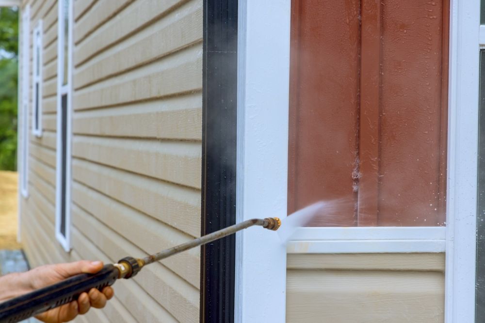 Pressure washer cleaning a brick house exterior and windows