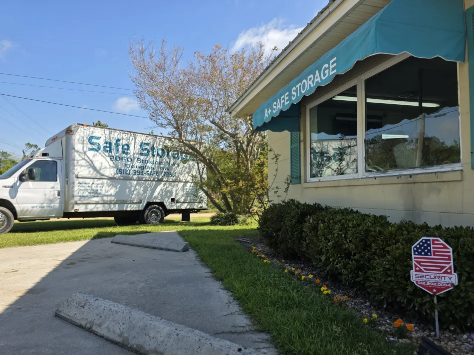 Truck parked beside a storefront with a teal awning on a sunny day