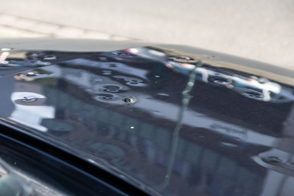 Rain-speckled Car Windshield Reflecting Nearby Buildings and Sky — Jackman's Bodyworks in Huonville, TAS