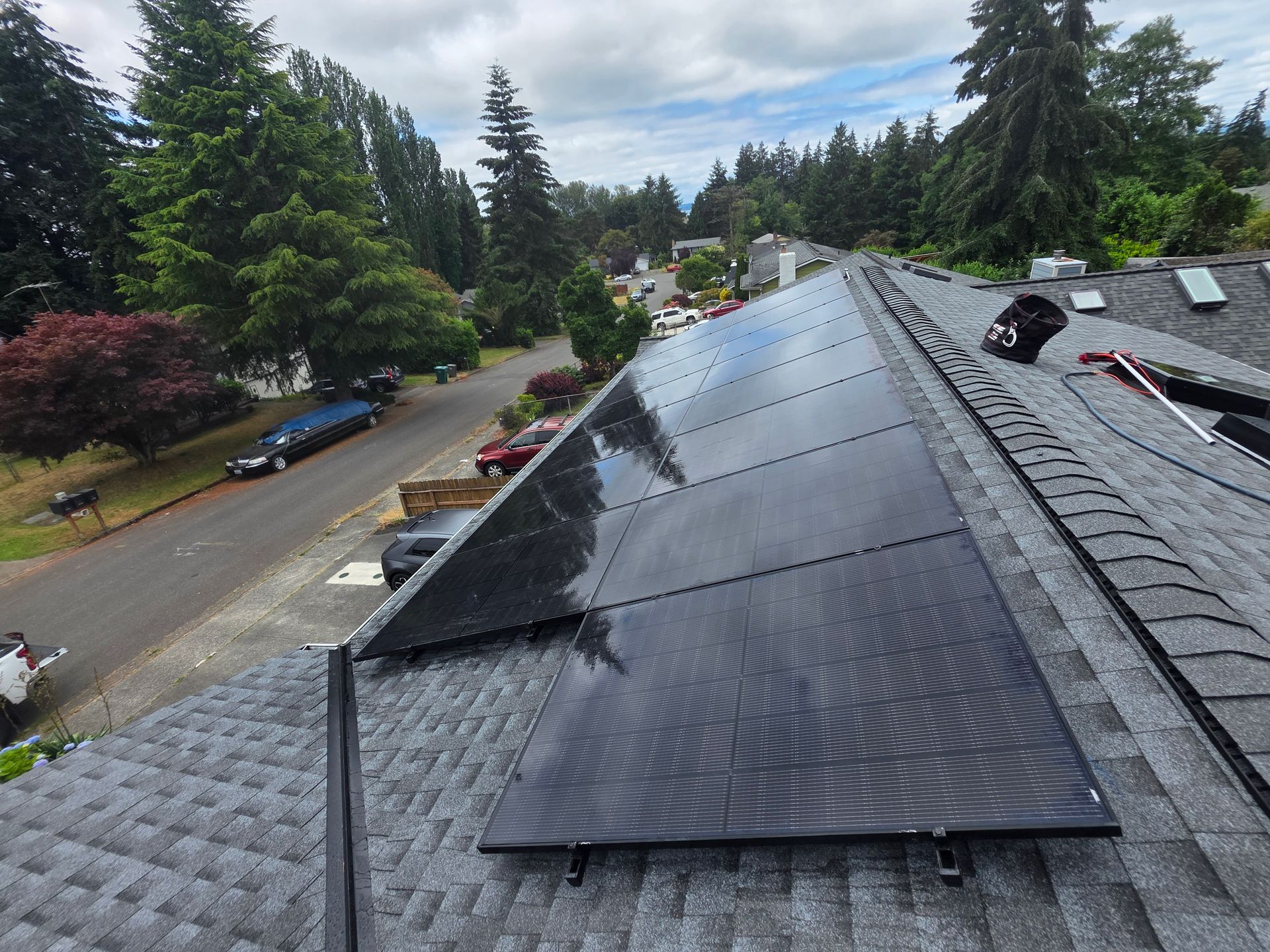 Two technicians reviewing plans beside rooftop solar panels in a suburban neighborhood